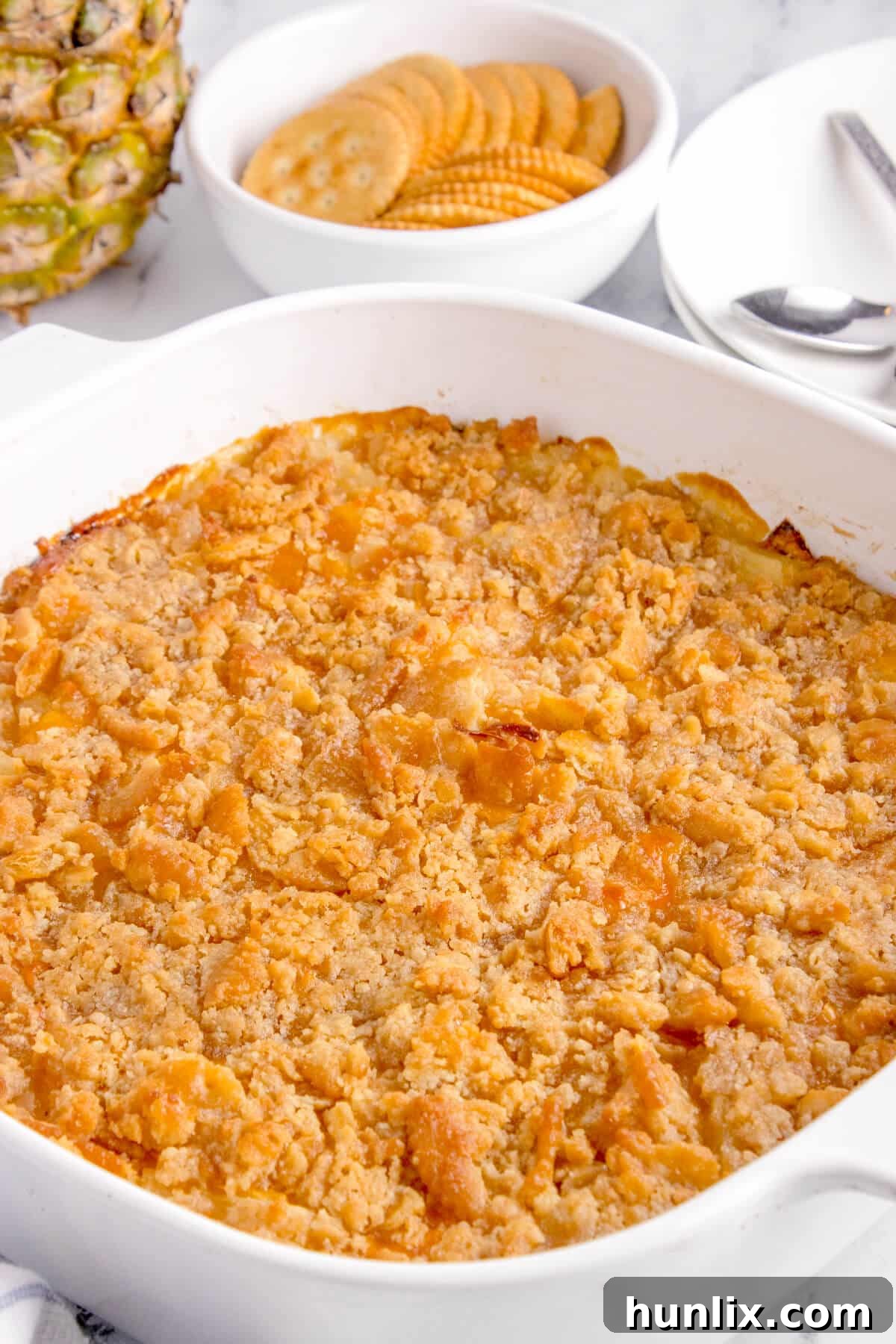 Pineapple casserole in a white baking dish, golden brown and bubbly, fresh from the oven.