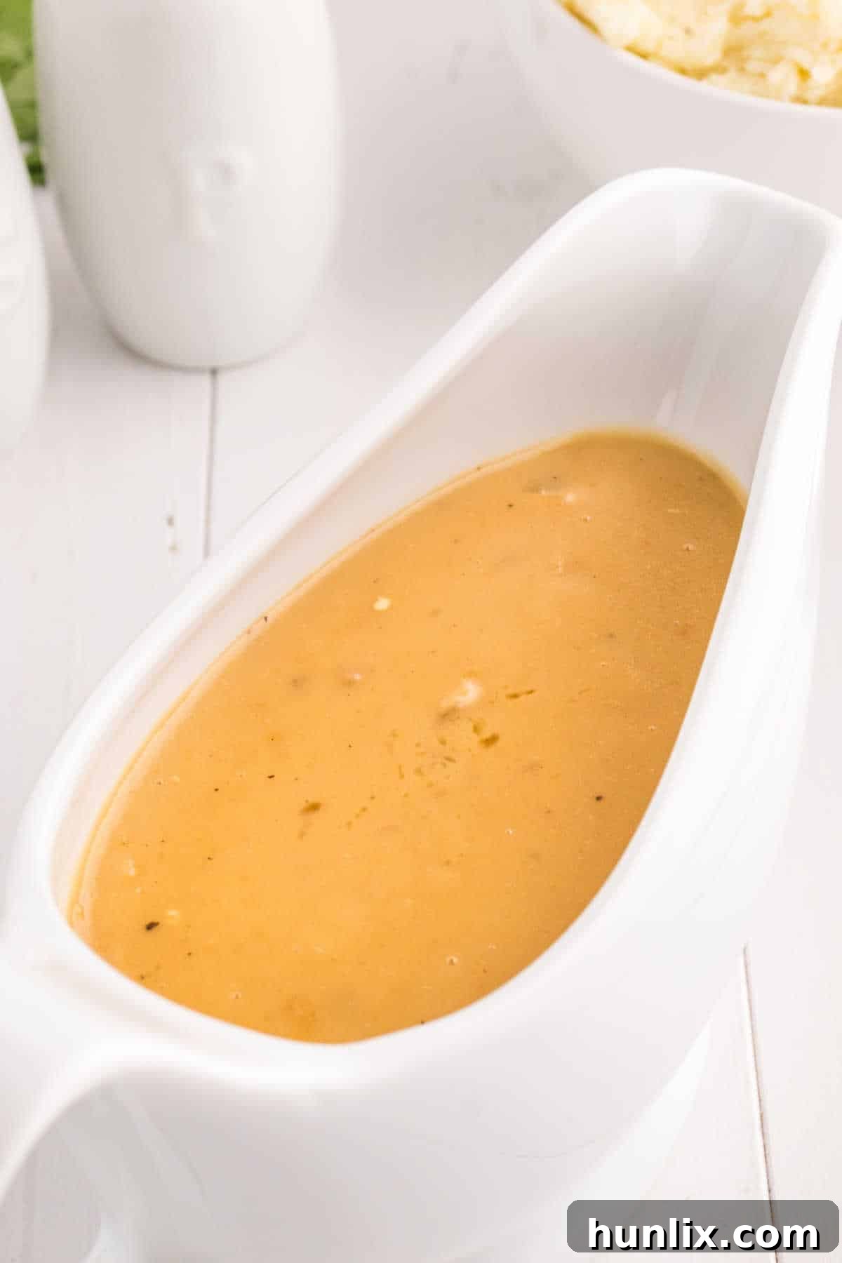 A pristine white gravy boat overflowing with luscious, homemade brown gravy, ready to be served.