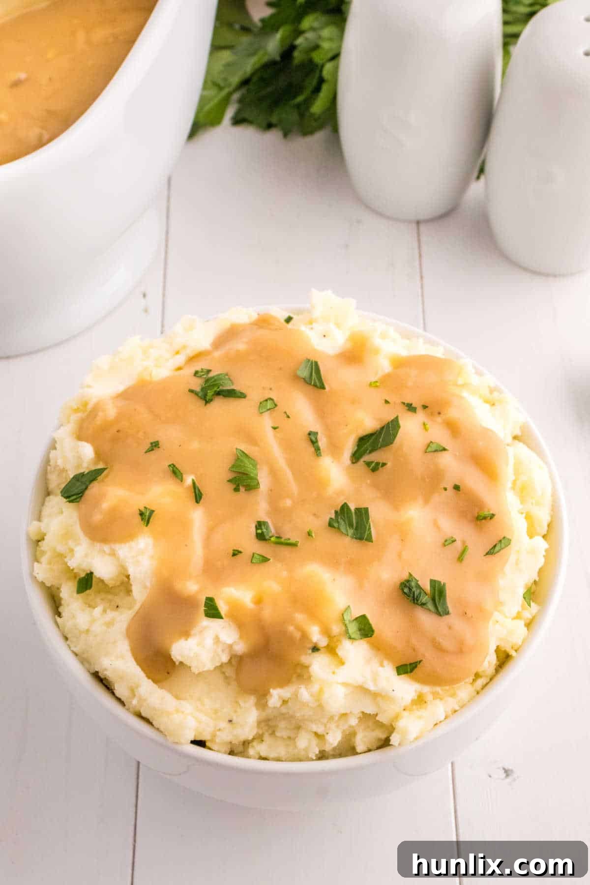 A close-up shot of a bowl of creamy mashed potatoes generously topped with rich, homemade brown gravy.