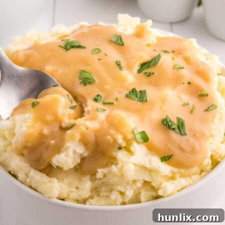 A bowl of mashed potatoes topped with brown gravy.