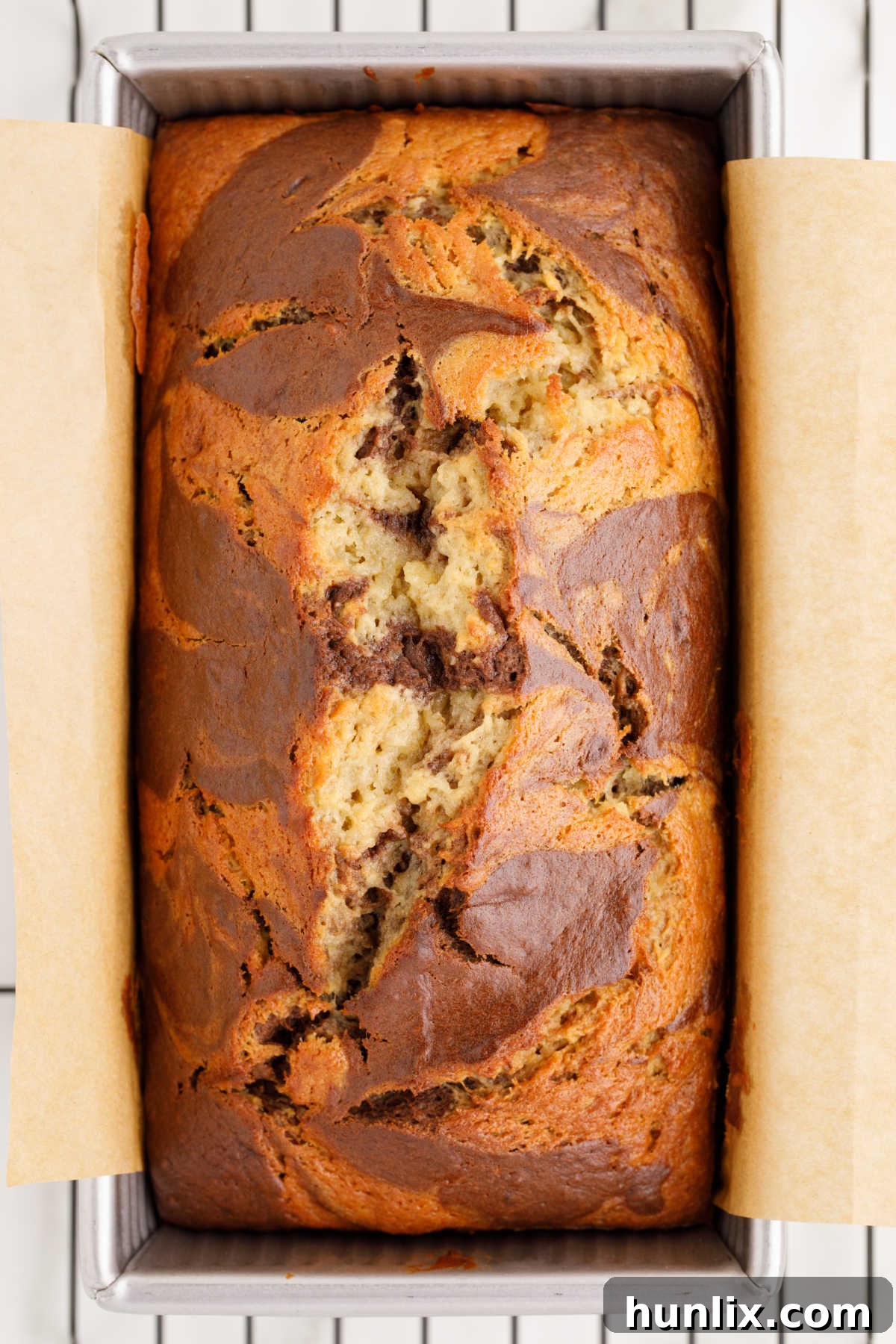 Moist marbled banana bread in a loaf pan, showcasing its beautiful two-toned swirls.