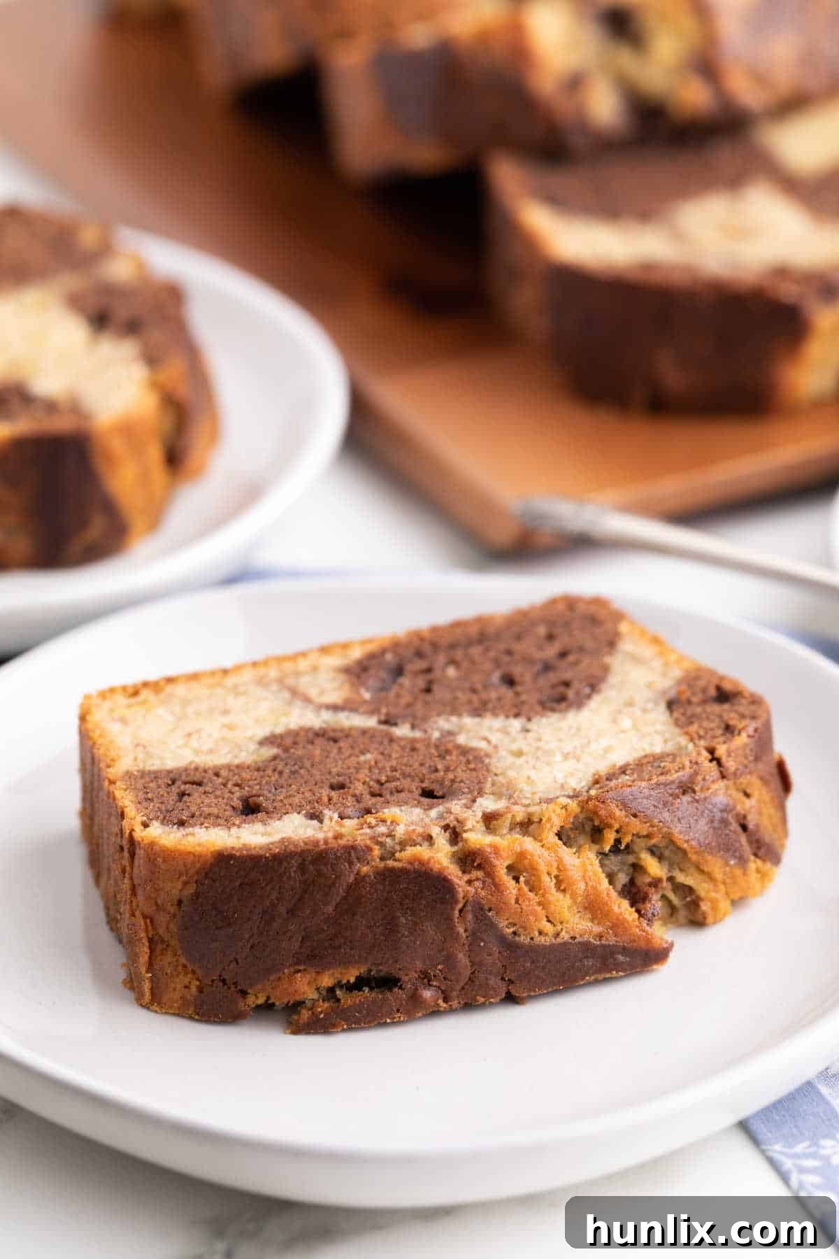A close-up of a single slice of marbled banana bread on a small plate.