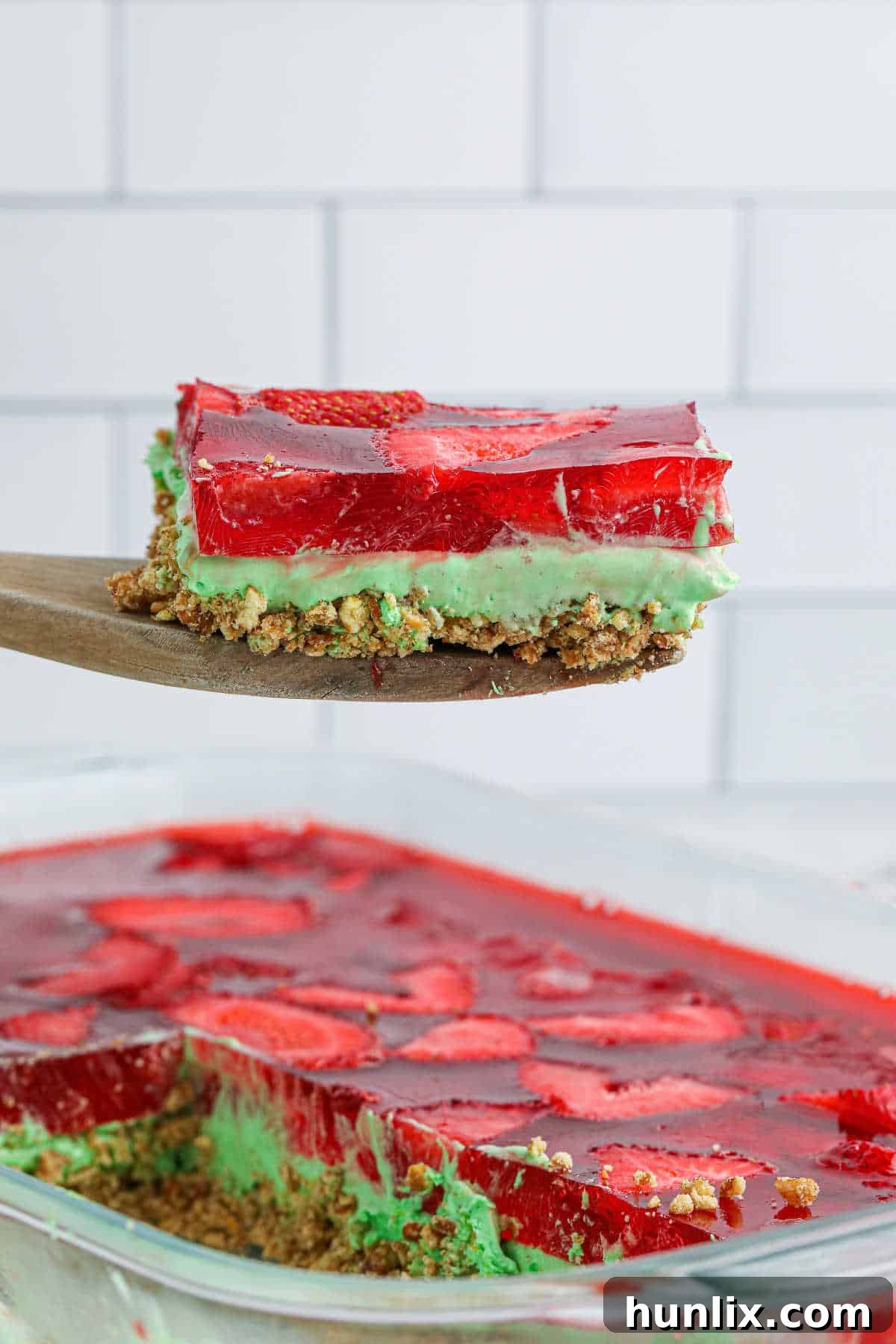 Sweet & Salty Christmas Pretzel Delight 2 A beautifully presented slice of Christmas Pretzel Salad on a wooden spoon, showcasing its distinct layers.