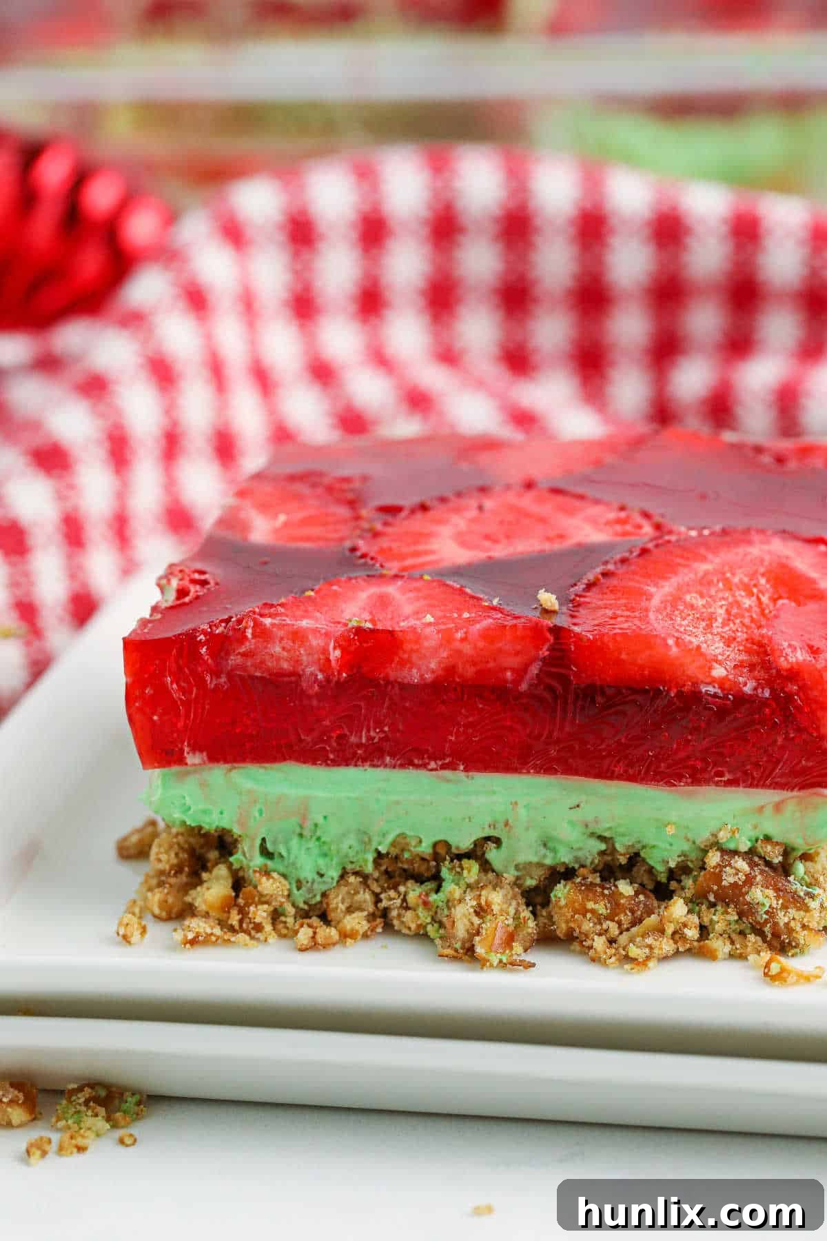 Sweet & Salty Christmas Pretzel Delight 9 A close-up of a perfectly cut slice of Christmas Pretzel Salad on a white plate, showcasing its layers.