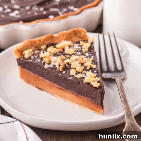 A top-down view of the whole chocolate caramel tart, garnished with flaky salt and ready to be sliced.