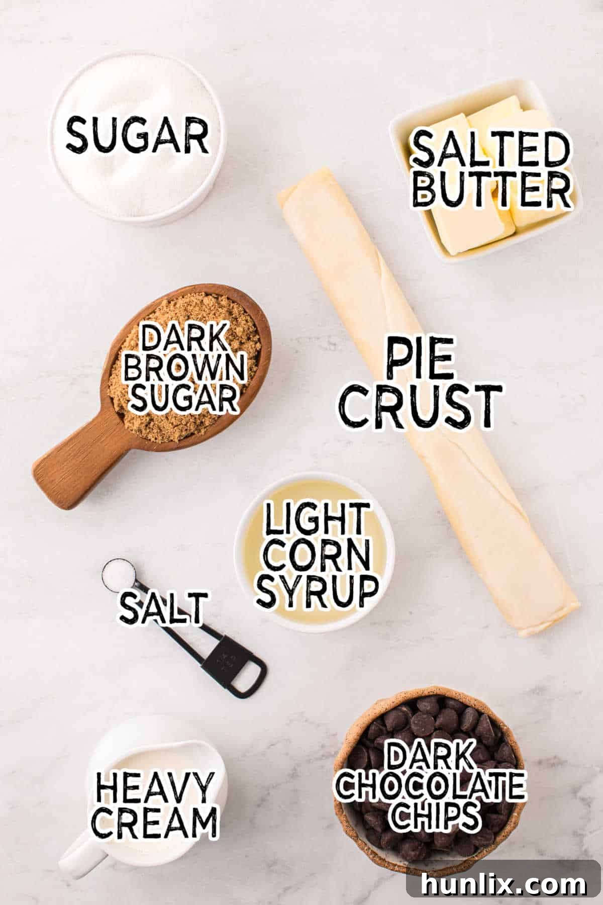 Individual ingredients neatly arranged on a white surface, ready to be used for making a chocolate caramel tart.