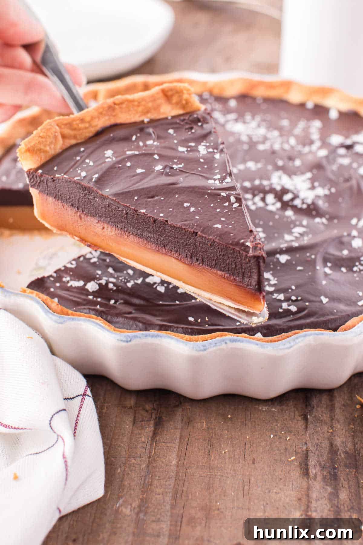 Another close-up of a chocolate caramel tart slice, showing the layers and the flaky salt topping.