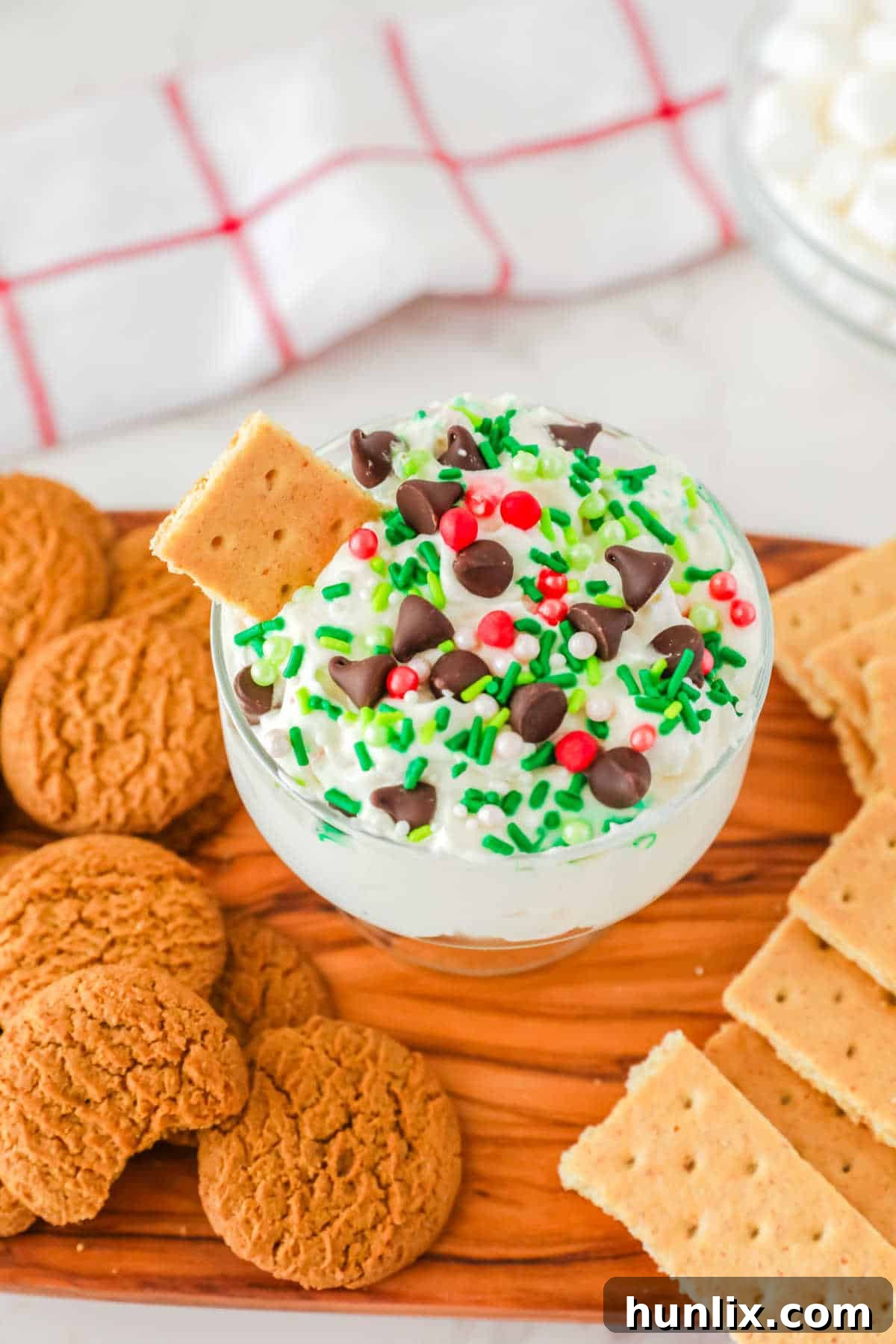 A dish of white chocolate elf fluff surrounded by various cookies, perfect for dipping.