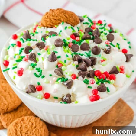 A bowl of white chocolate elf fluff, garnished with chocolate chips and Christmas sprinkles.