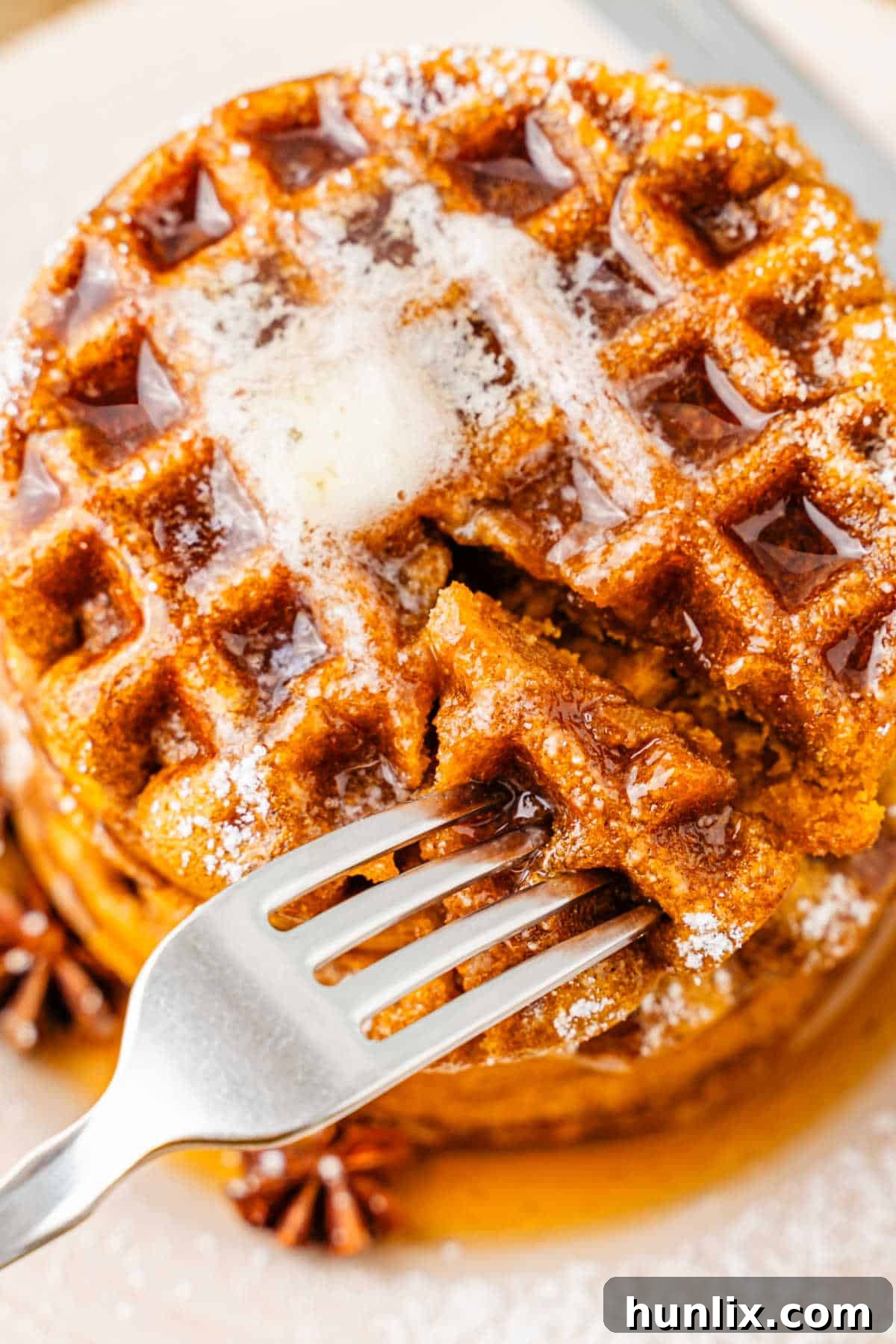 Gingerbread waffles with a fork inserted, showing their fluffy texture.
