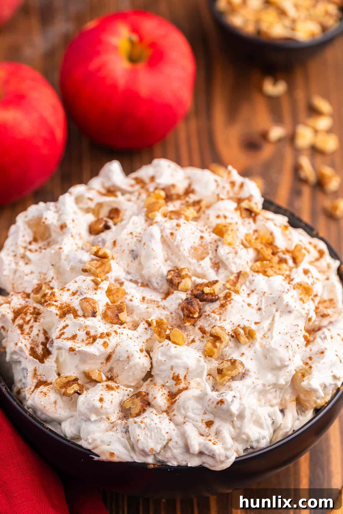 A close-up of a spoonful of Apple Pie Fluff, showing its light and airy texture with visible apple pieces and walnuts.
