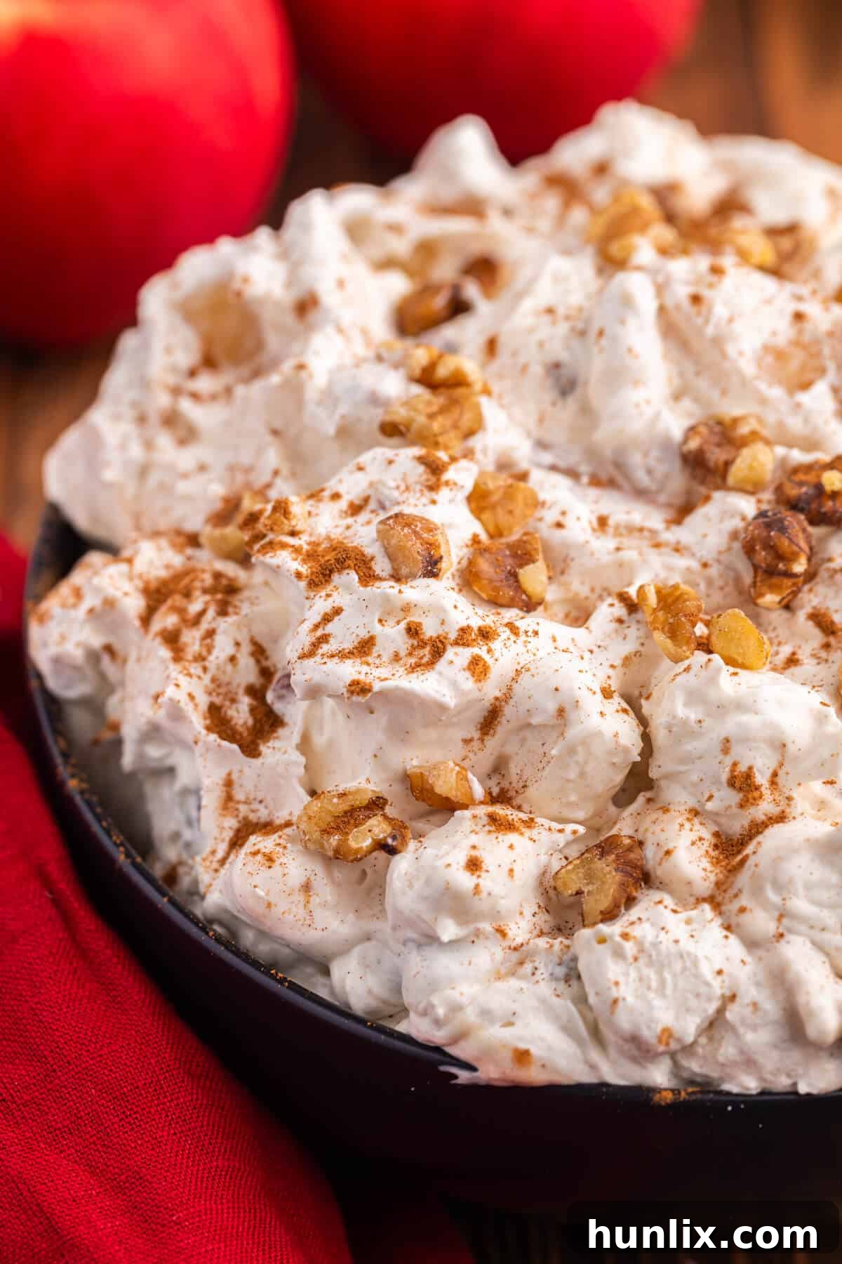 A bowl of Apple Pie Fluff on a rustic wooden surface, garnished and ready to be enjoyed.