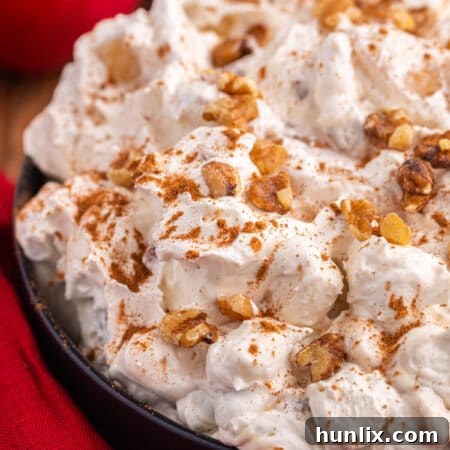 A full bowl of Apple Pie Fluff, garnished with cinnamon and walnuts.