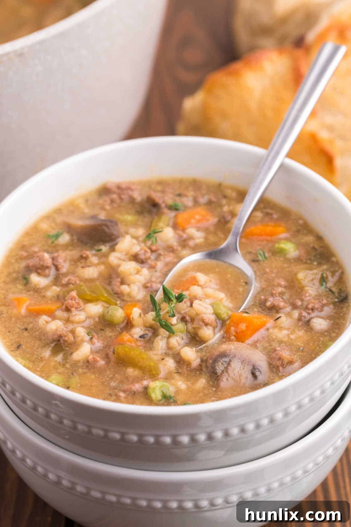 Hearty Beef and Barley Comfort Soup 6 A bowl of beef and barley soup with a spoon.