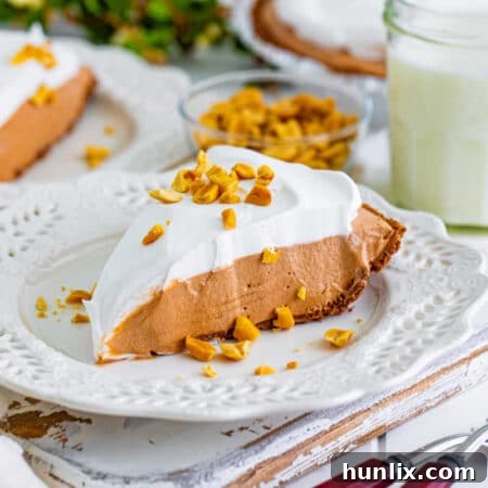 A beautifully decorated whole chocolate peanut butter pie with a slice cut out, ready to be served.