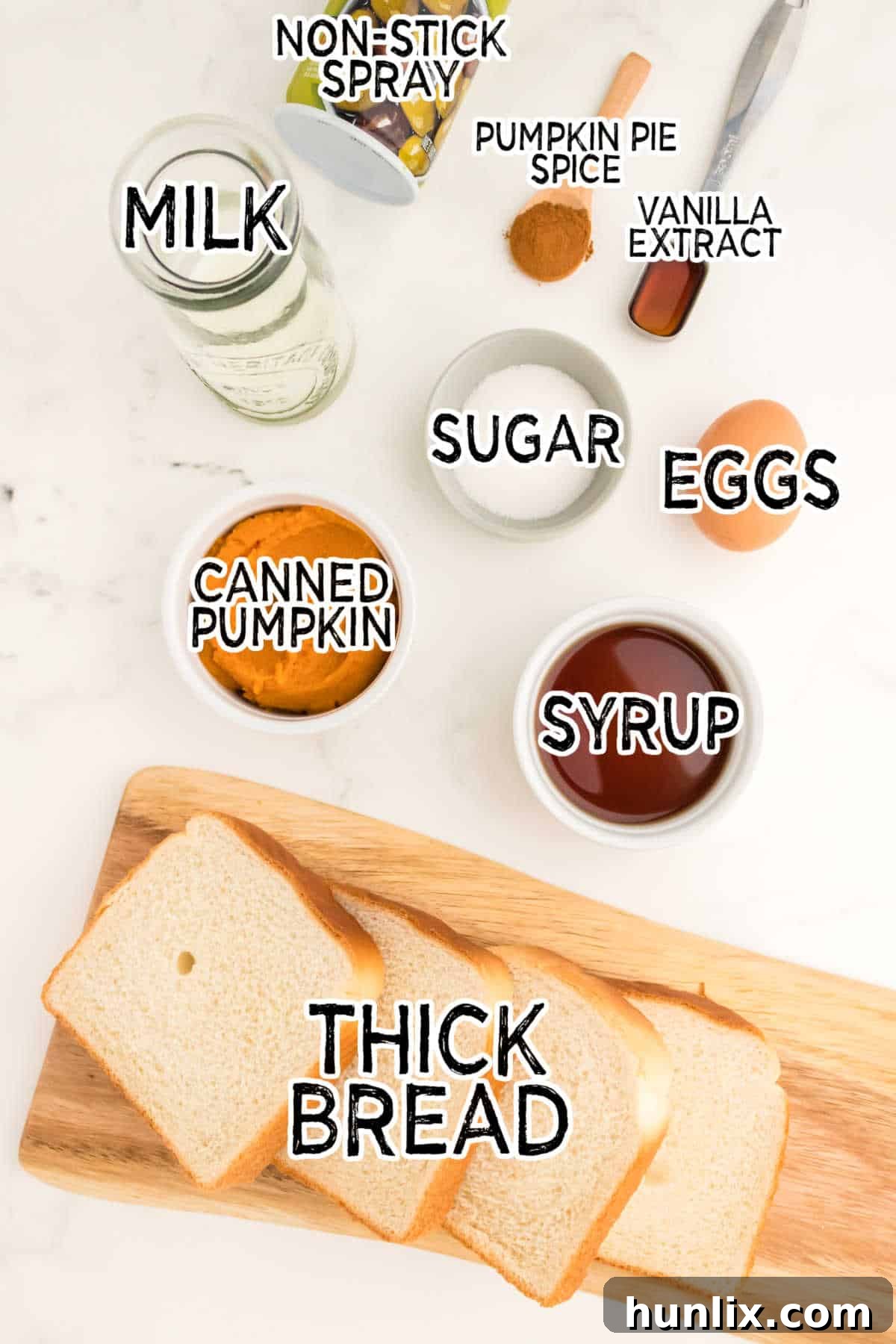 A selection of fresh ingredients including eggs, pumpkin puree, milk, and spices on a white surface, ready for making French toast.