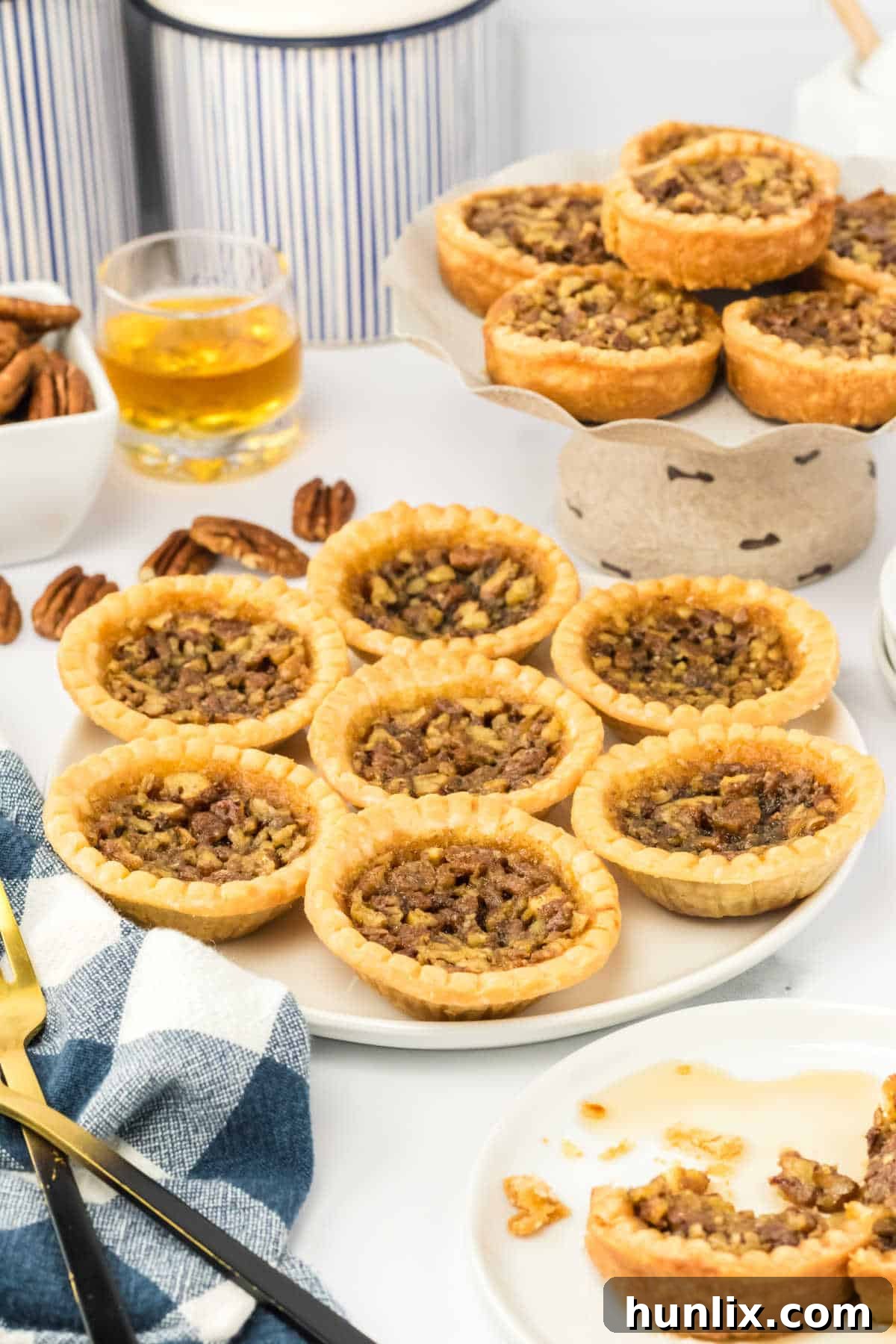 Decadent Bourbon Pecan Tarts 6 Pecan bourbon butter tarts on a plate.