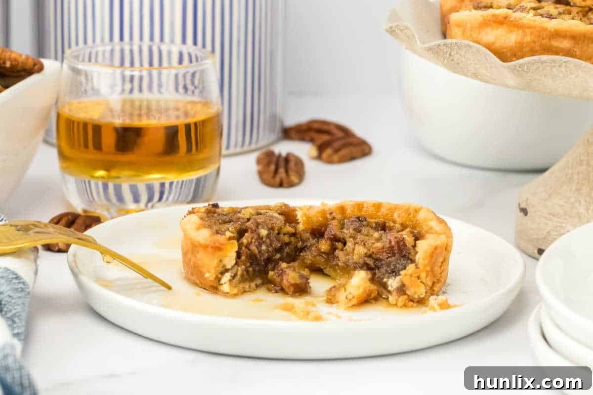 Decadent Bourbon Pecan Tarts 7 A pecan bourbon butter tart cut in half on a plate.