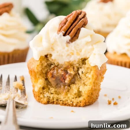 A beautifully frosted pecan pie cupcake on a small plate.