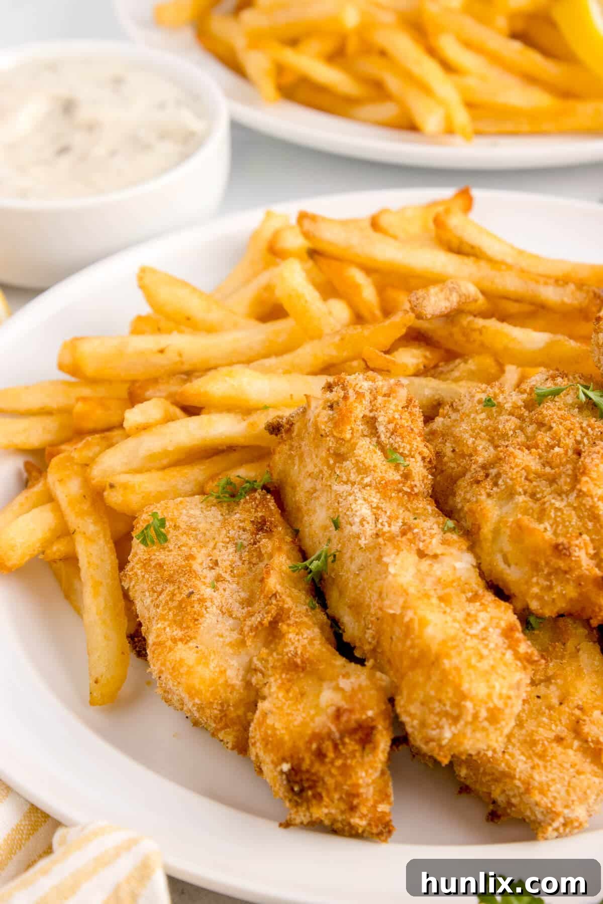 The air-fried fish sticks served on a plate with crispy French Fries.