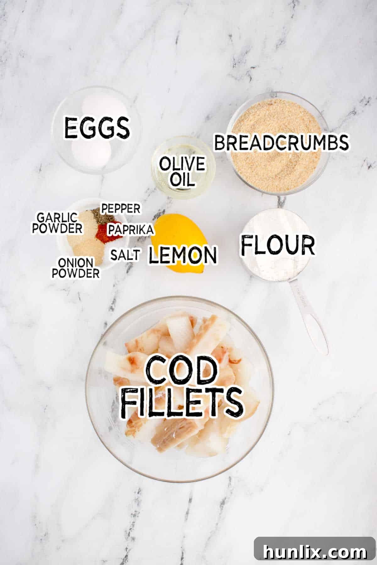 Assortment of fresh ingredients for air fryer fish sticks on a white marble counter.