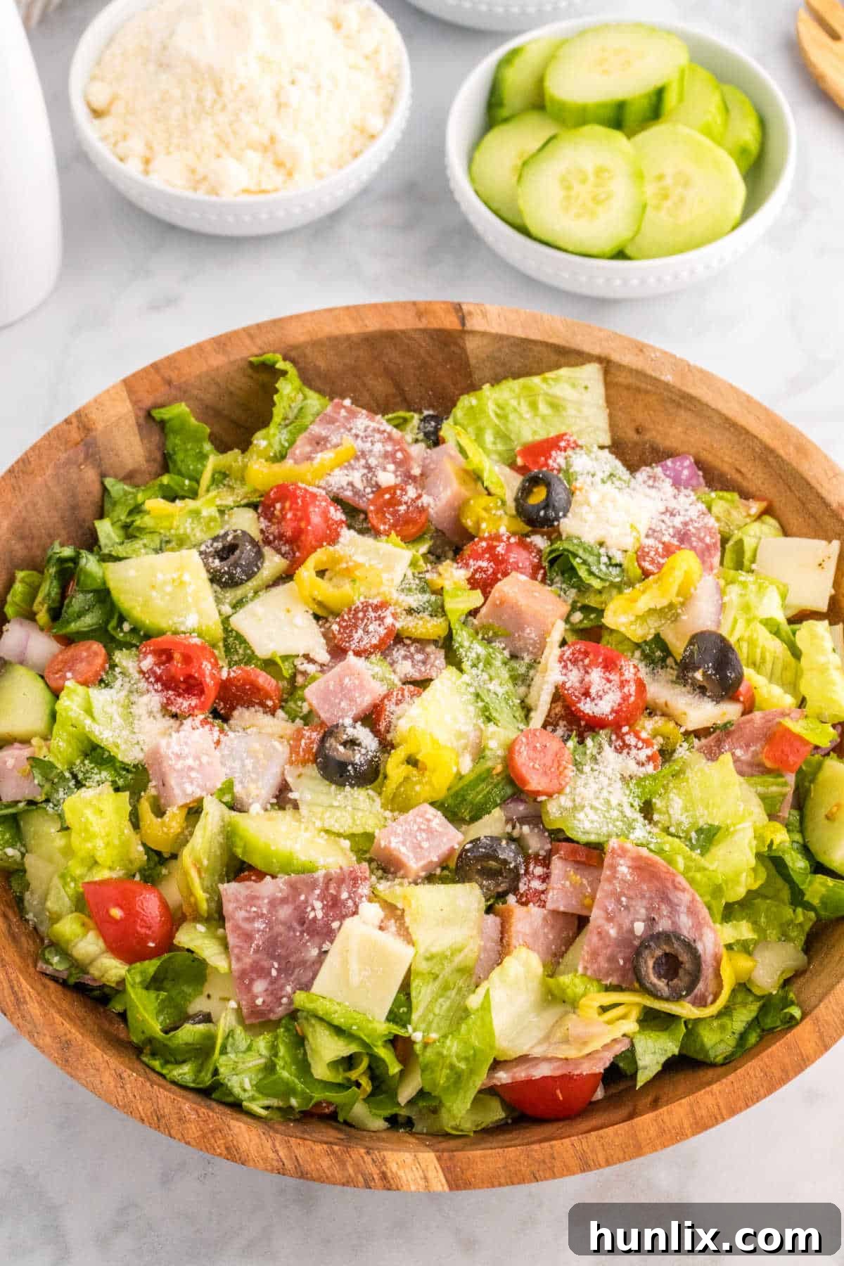 Close-up of Italian sub salad in a wooden bowl, highlighting textures.