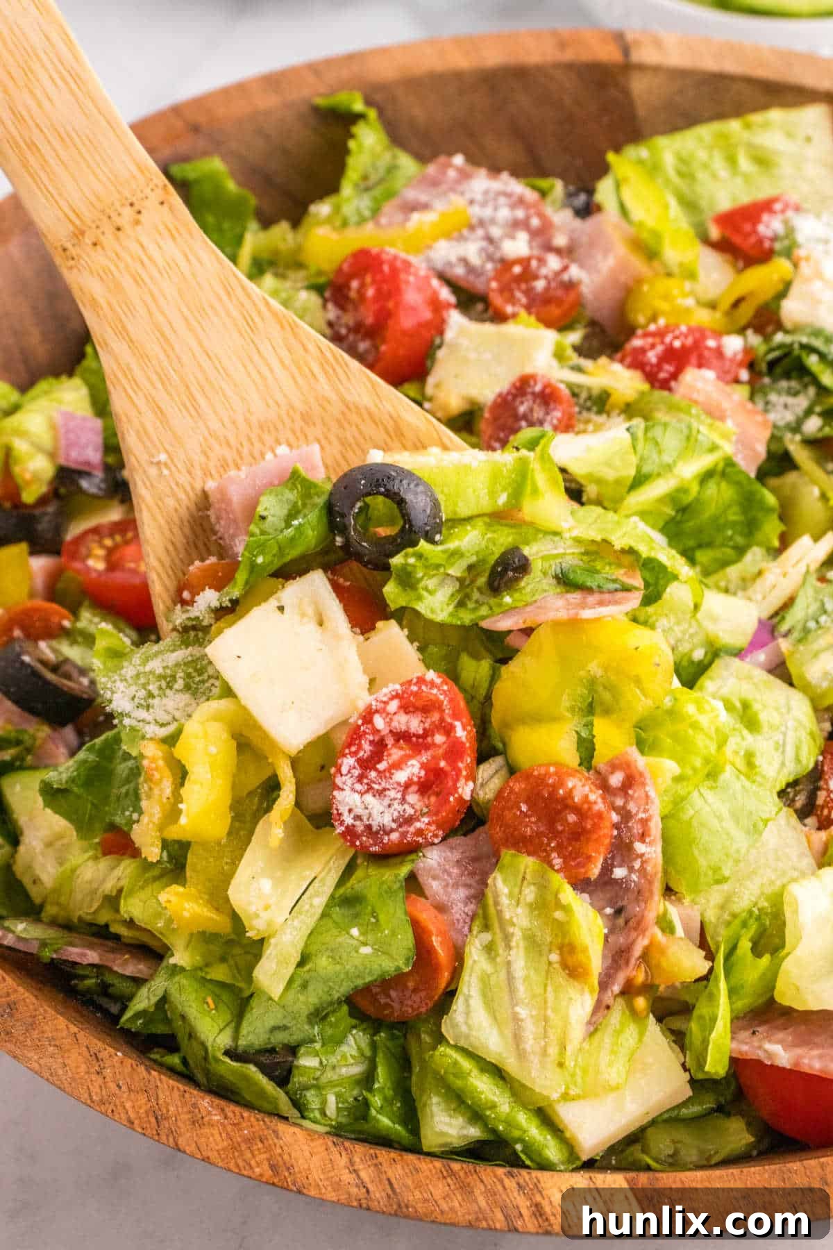 Italian sub salad in a bowl with a wooden spoon, ready to serve.