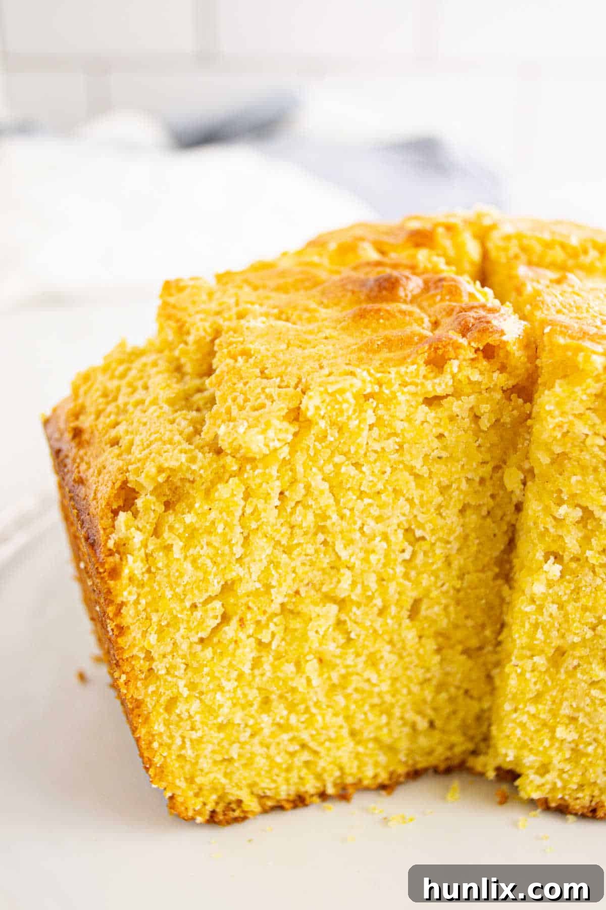 A slice of Southern Corn Cake removed from the pan, showing its moist interior.