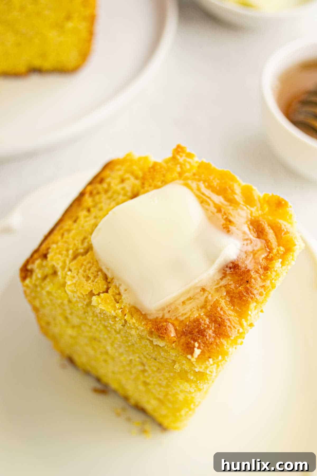 A piece of Southern Corn Cake topped with a melting pat of butter.