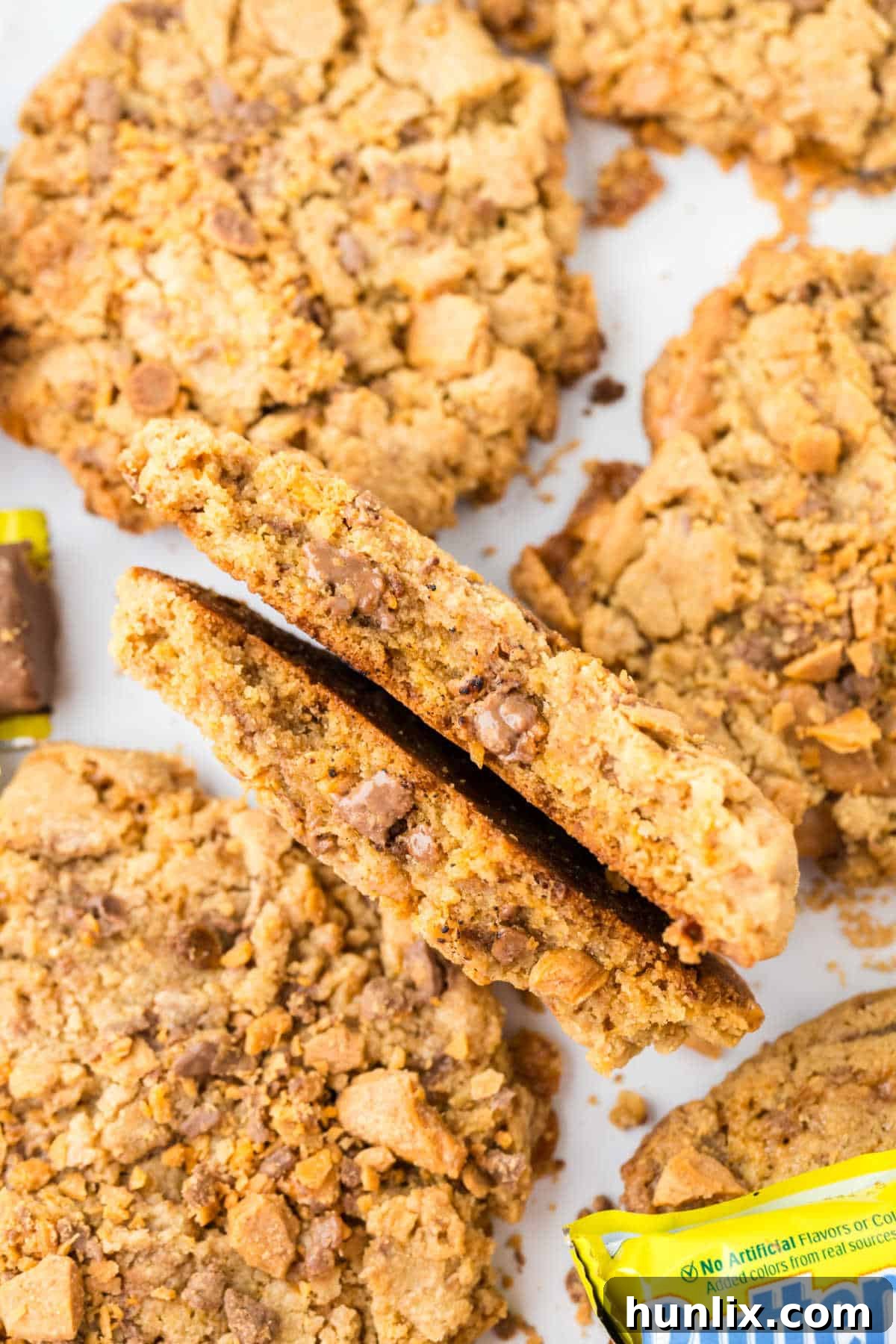 A Butterfinger cookie broken in half to show the chewy interior and candy bits.