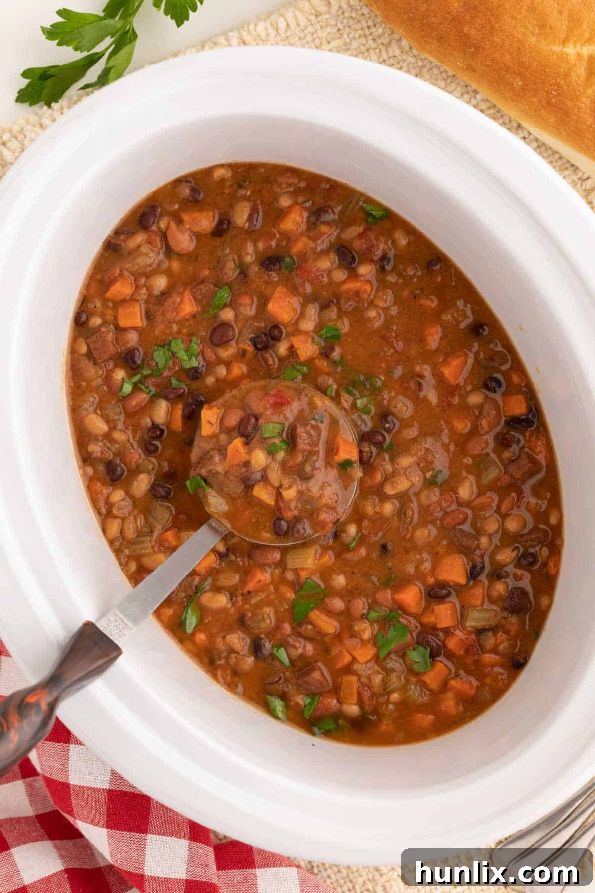 Ham and bean soup in a crockpot, steaming warmly.