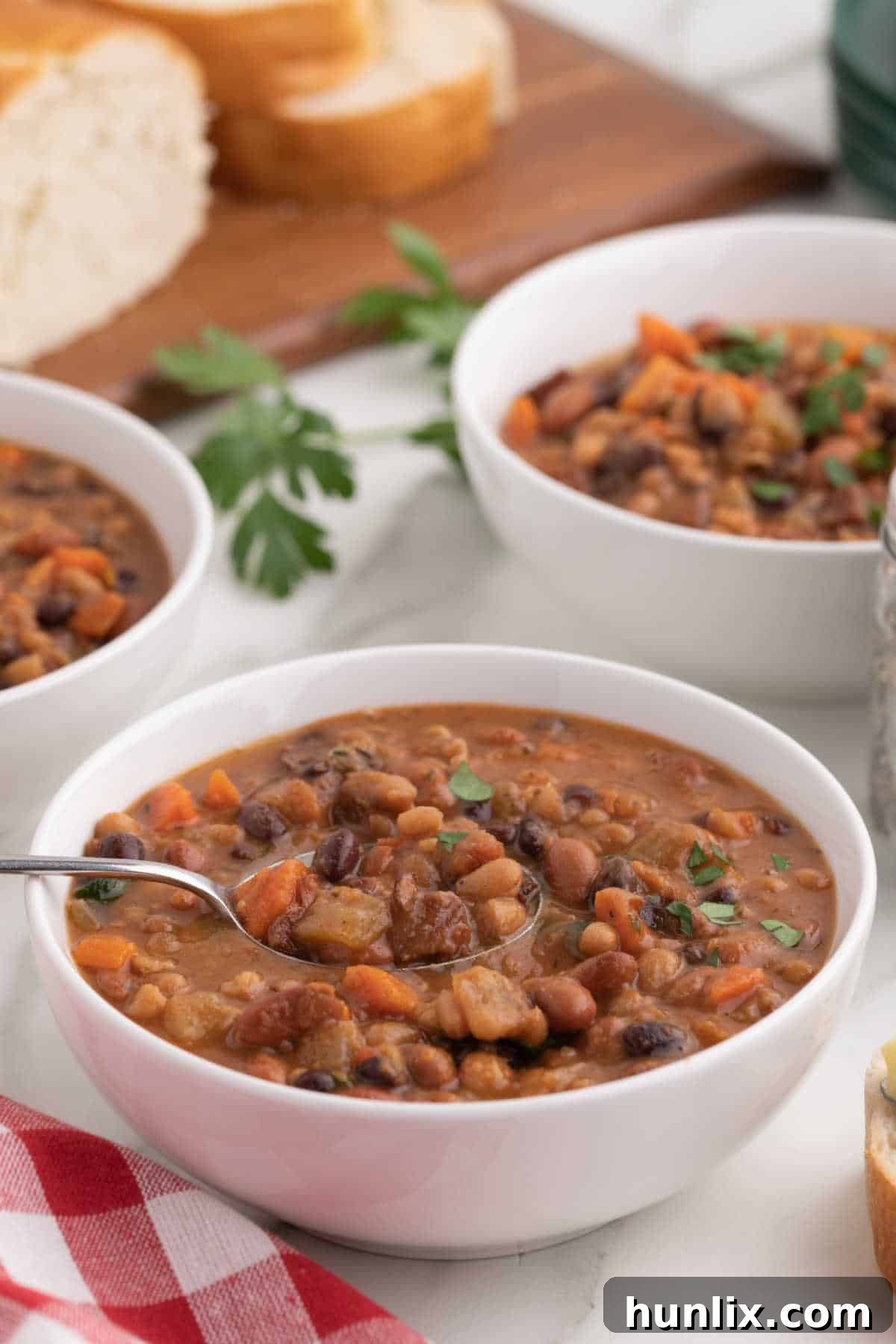 A bowl of crockpot ham and bean soup with a spoon resting in it.
