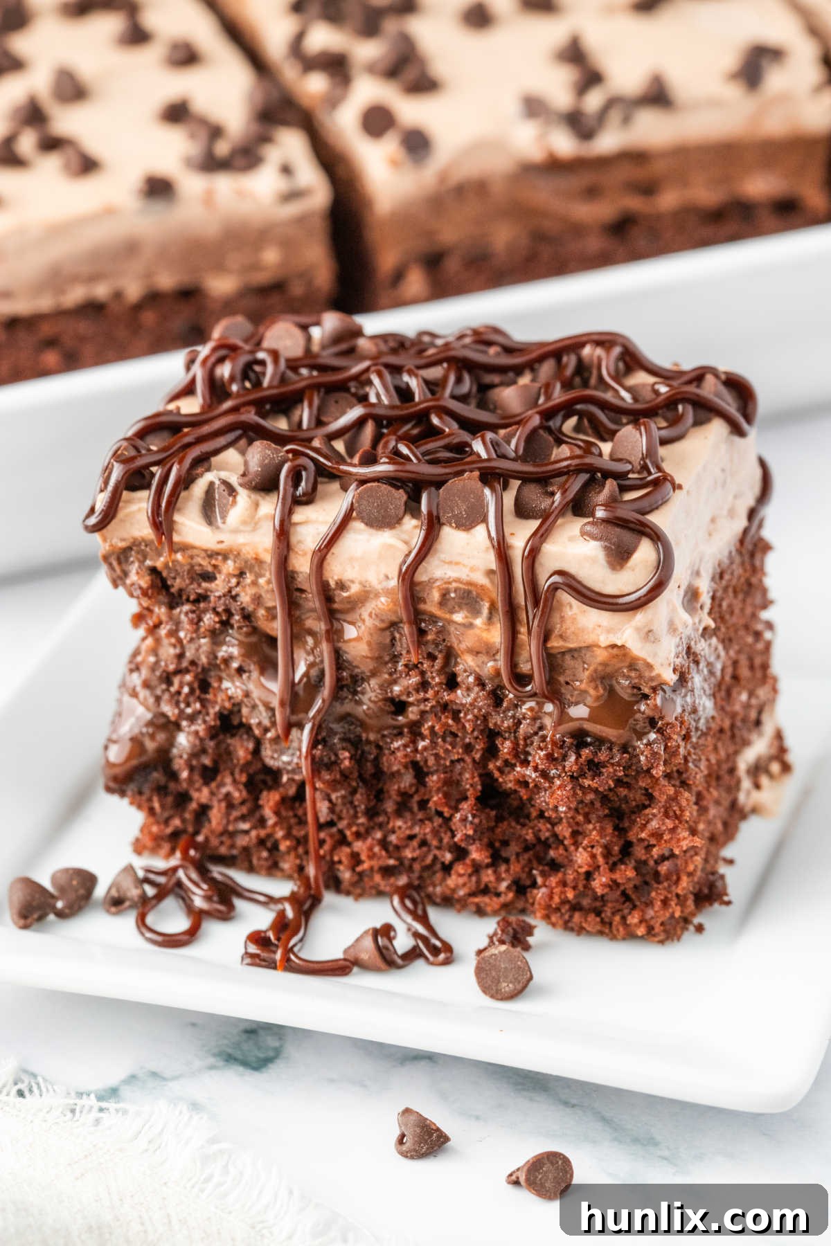 Decadent Triple Chocolate Poke Cake 2 A piece of triple chocolate poke cake on a plate.