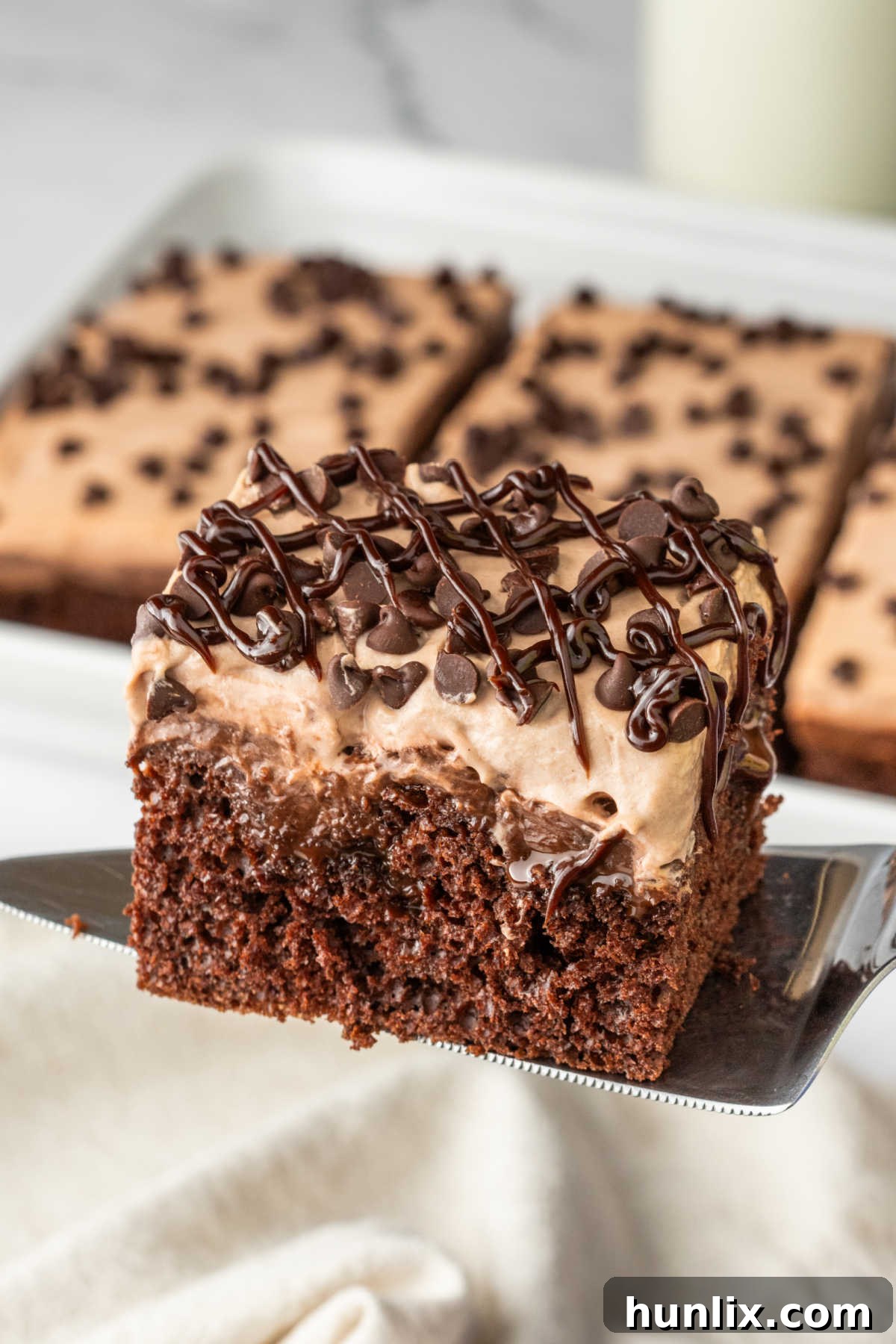 Decadent Triple Chocolate Poke Cake 9 A piece of cake on a serving spatula.