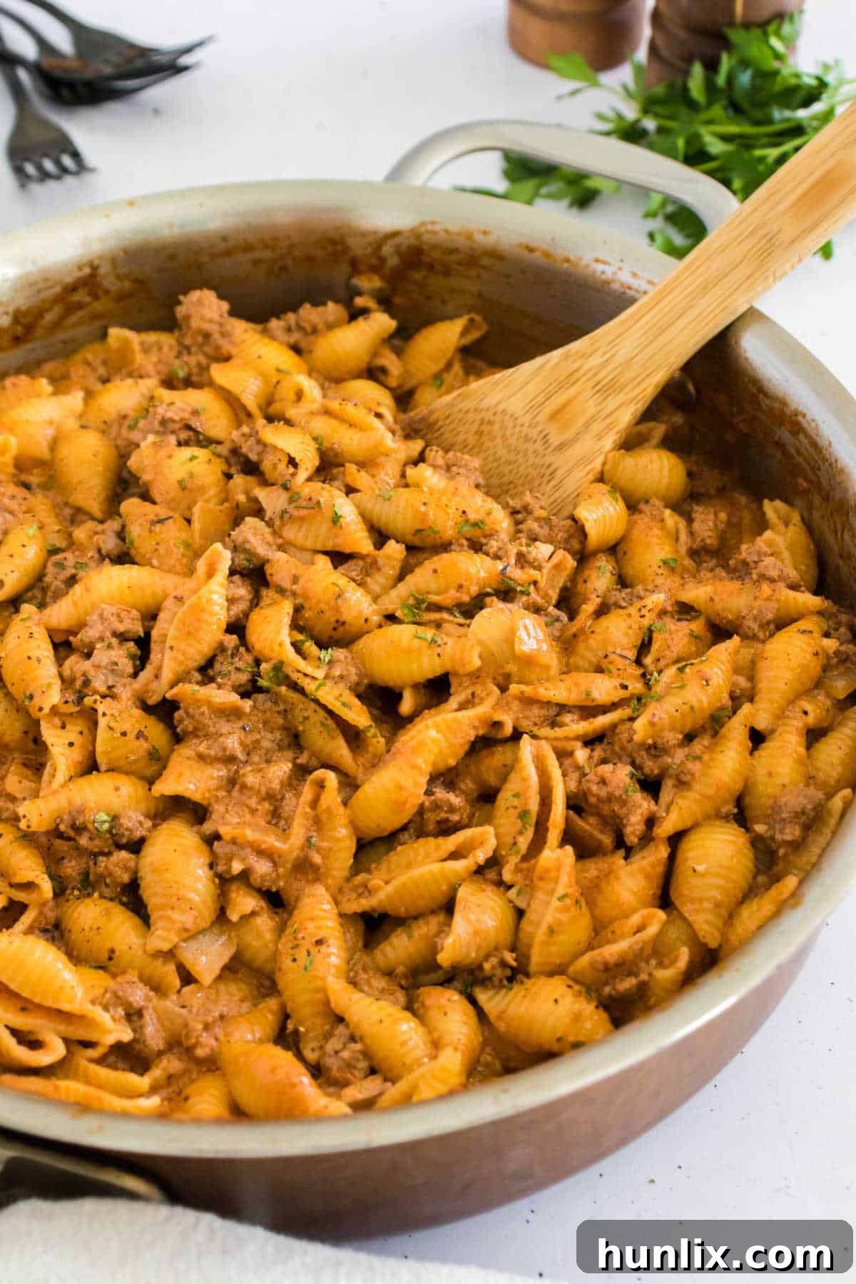 Creamy beef and shells in a large pot with a serving spoon, ready to be dished out.
