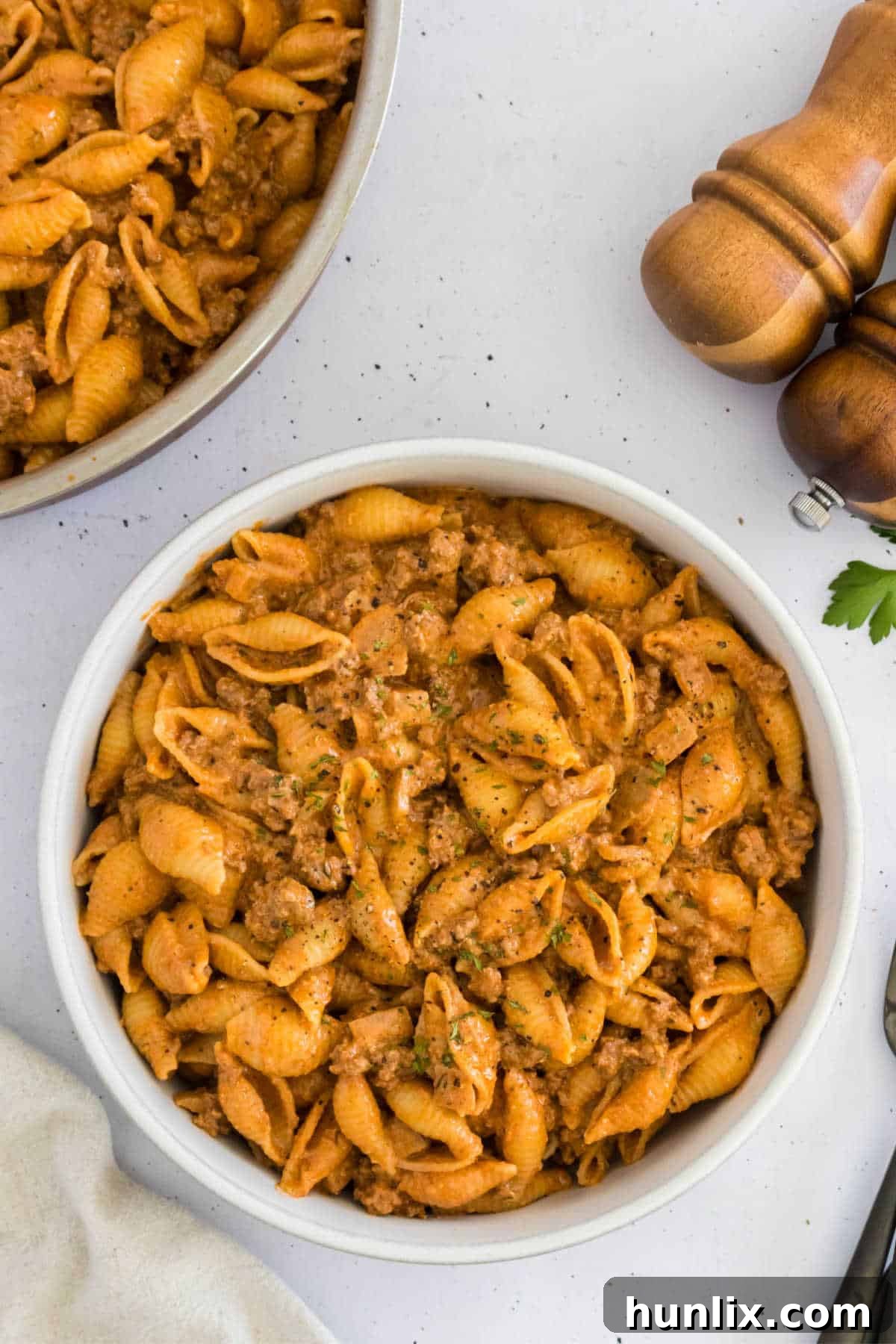 Creamy beef and shells served in a white bowl, garnished with fresh parsley.