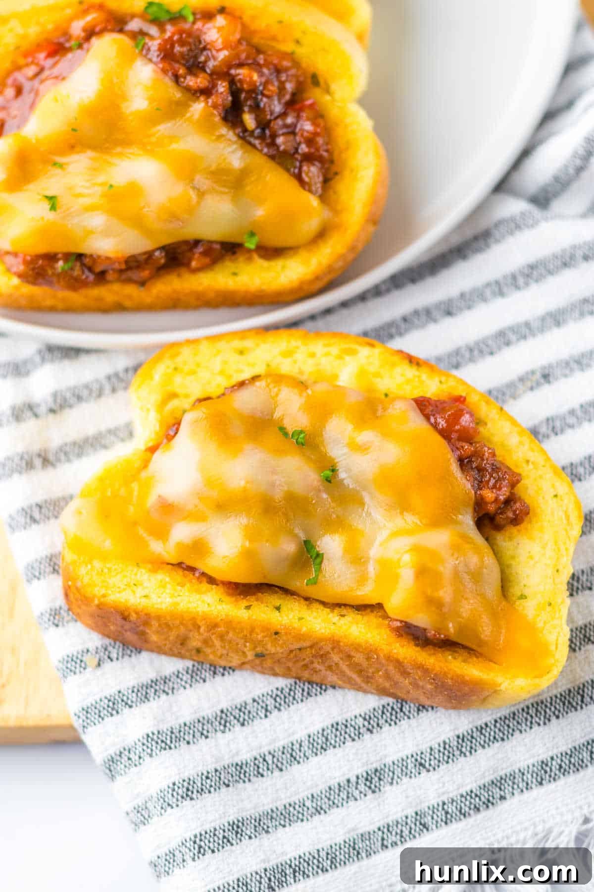 A close-up of a Texas Toast sloppy joe placed on a napkin, highlighting its cheesy and meaty filling.