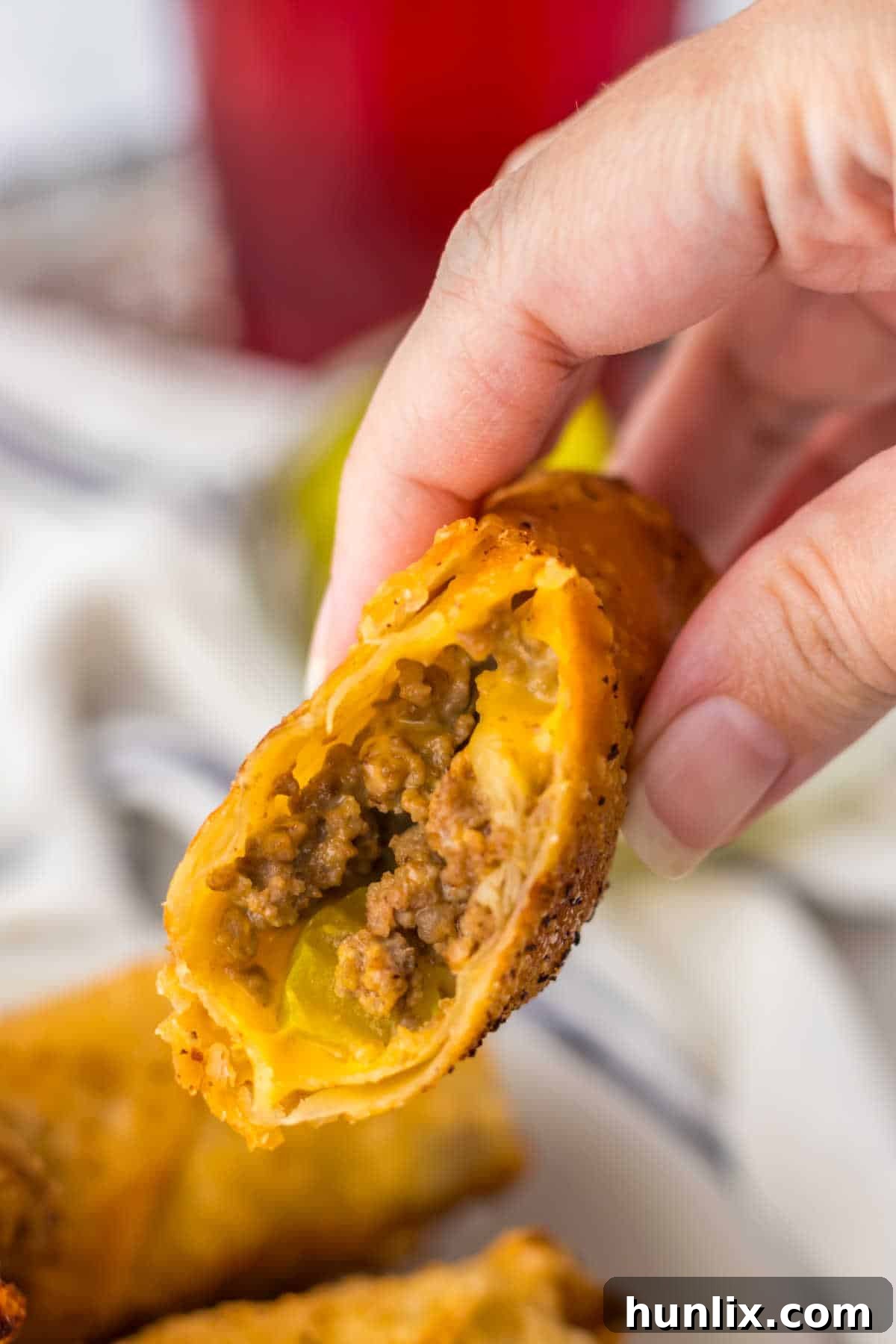 A hand holding a Big Mac Egg Roll that's been cut in half.