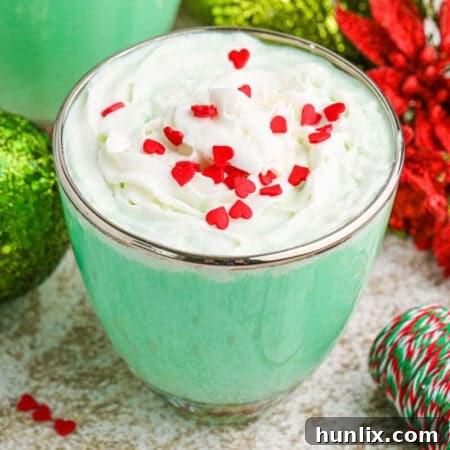 The Grinch Mint Cocktail in a glass mug, topped with whipped cream and red sprinkles.