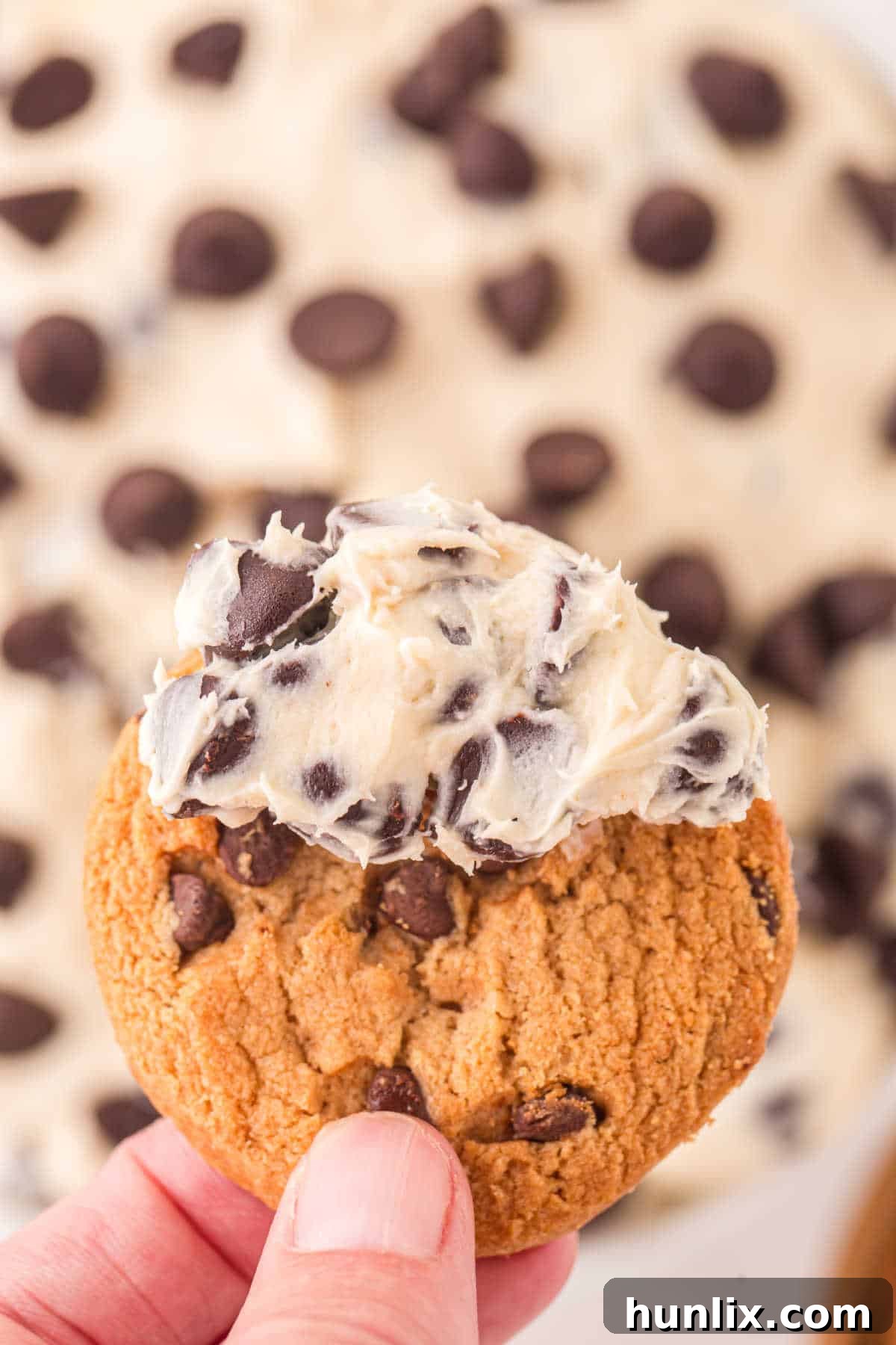 No-Bake Cookie Dough Dip 8 A close-up shot of a single chocolate chip cookie resting on a generous scoop of cookie dough dip, highlighting the creamy texture and chocolate chips.