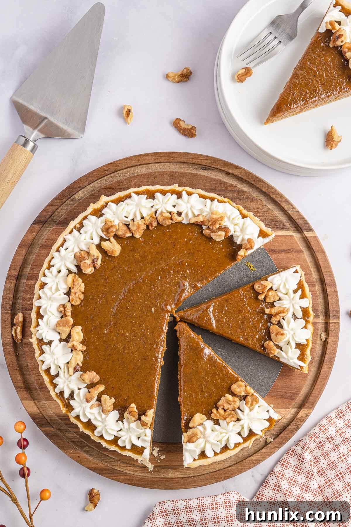 A slice of golden pumpkin tart on a plate, adorned with a dollop of whipped cream and a sprinkle of cinnamon, ready to be enjoyed.