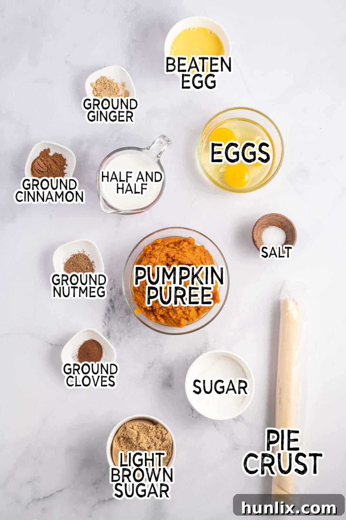 An array of fresh baking ingredients including pumpkin puree, spices, eggs, and sugars laid out on a kitchen counter, ready for tart preparation.