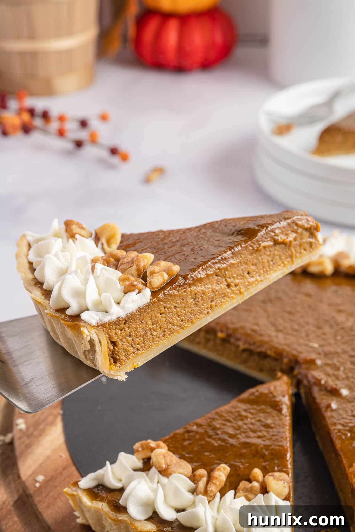 A perfectly cut slice of pumpkin tart being lifted from the pan with a spatula, showcasing its creamy filling and crisp crust.