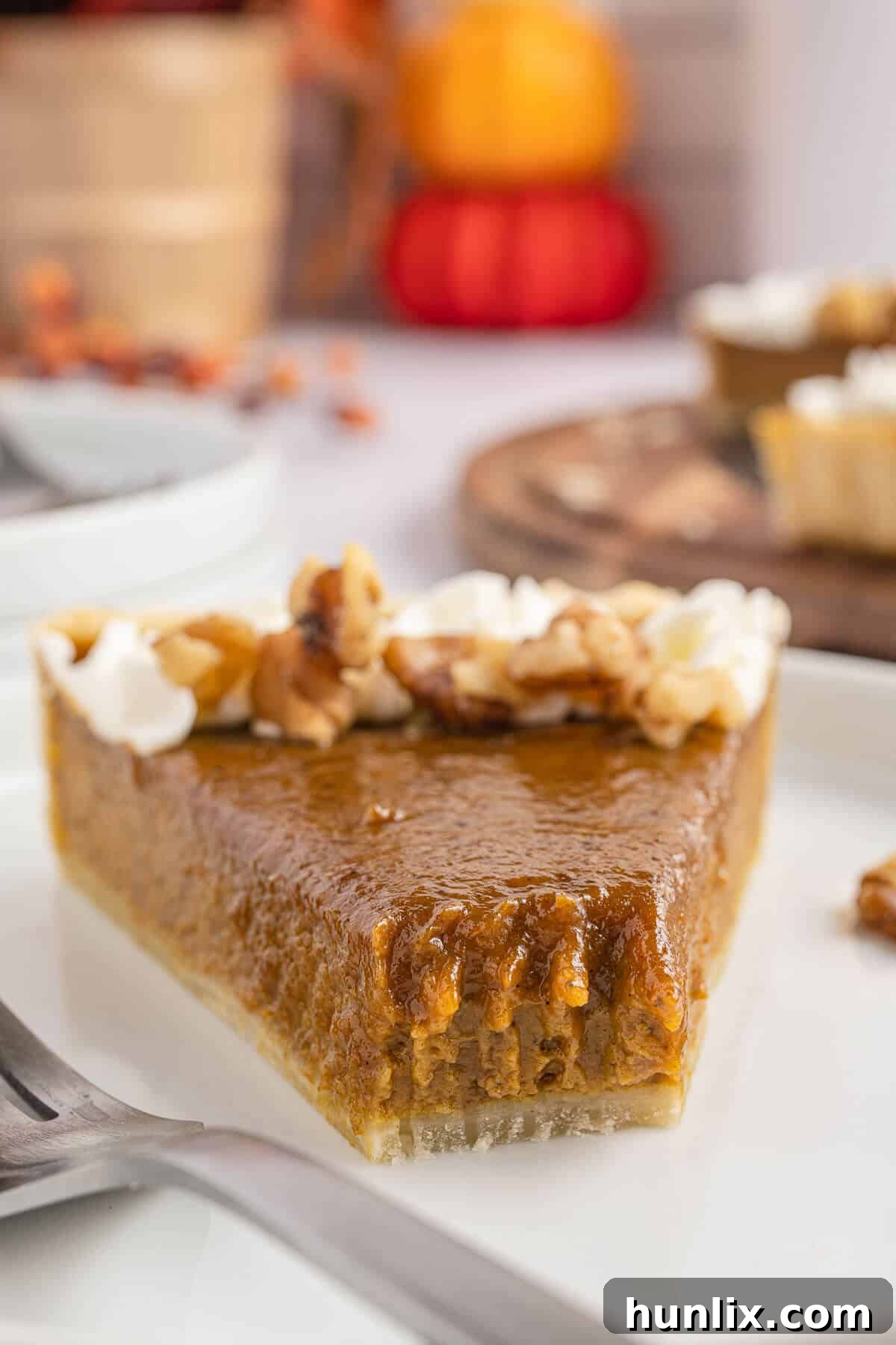 A slice of the perfectly baked pumpkin tart on a plate, with a small bite taken from the end, highlighting its creamy texture.