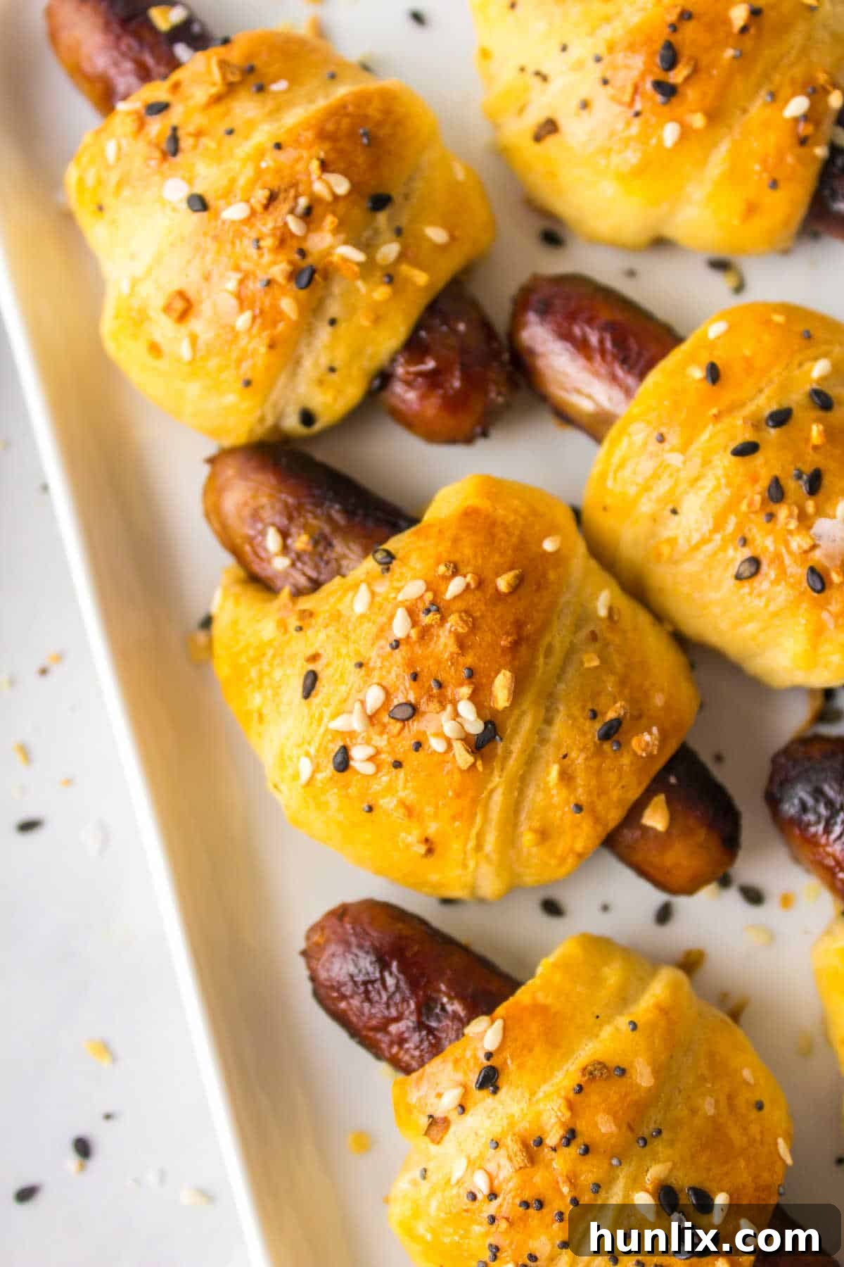 Breakfast pigs in a blanket arranged beautifully on a serving platter.