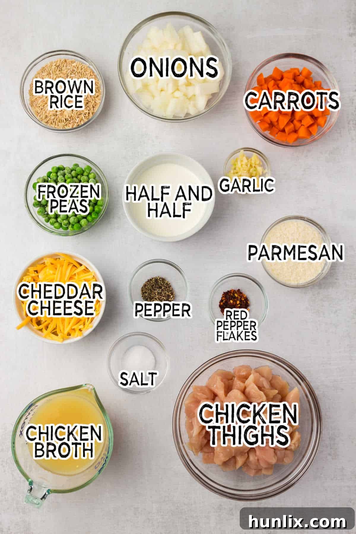 Set-It-and-Forget-It Chicken and Rice 3 A selection of fresh ingredients including chicken, vegetables, rice, and cheese on a grey background.