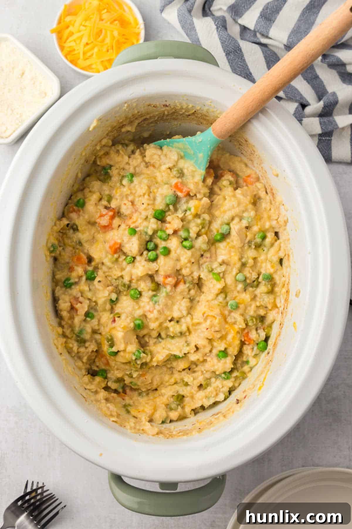Set-It-and-Forget-It Chicken and Rice 7 The finished Crockpot Chicken and Rice recipe in the crockpot with a wooden spoon for serving.