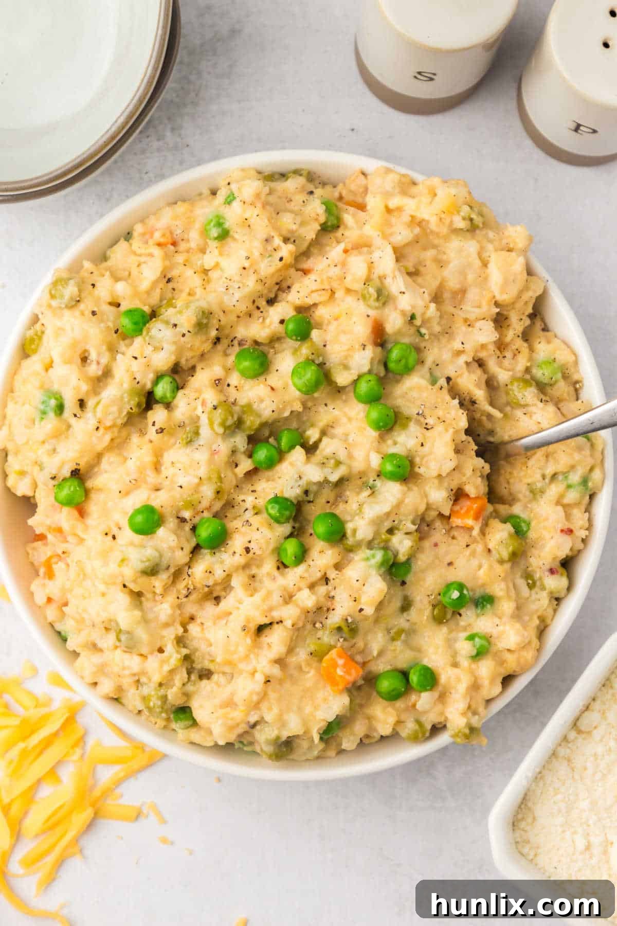 Set-It-and-Forget-It Chicken and Rice 8 A bowl of Crockpot Chicken and Rice served with a spoon, highlighting its creamy, cheesy texture.