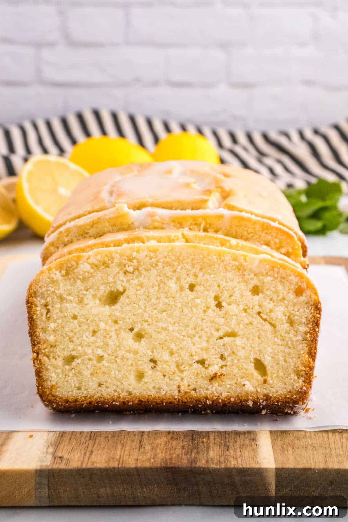 Several slices of Iced Lemon Pound Cake arranged on a wooden cutting board.