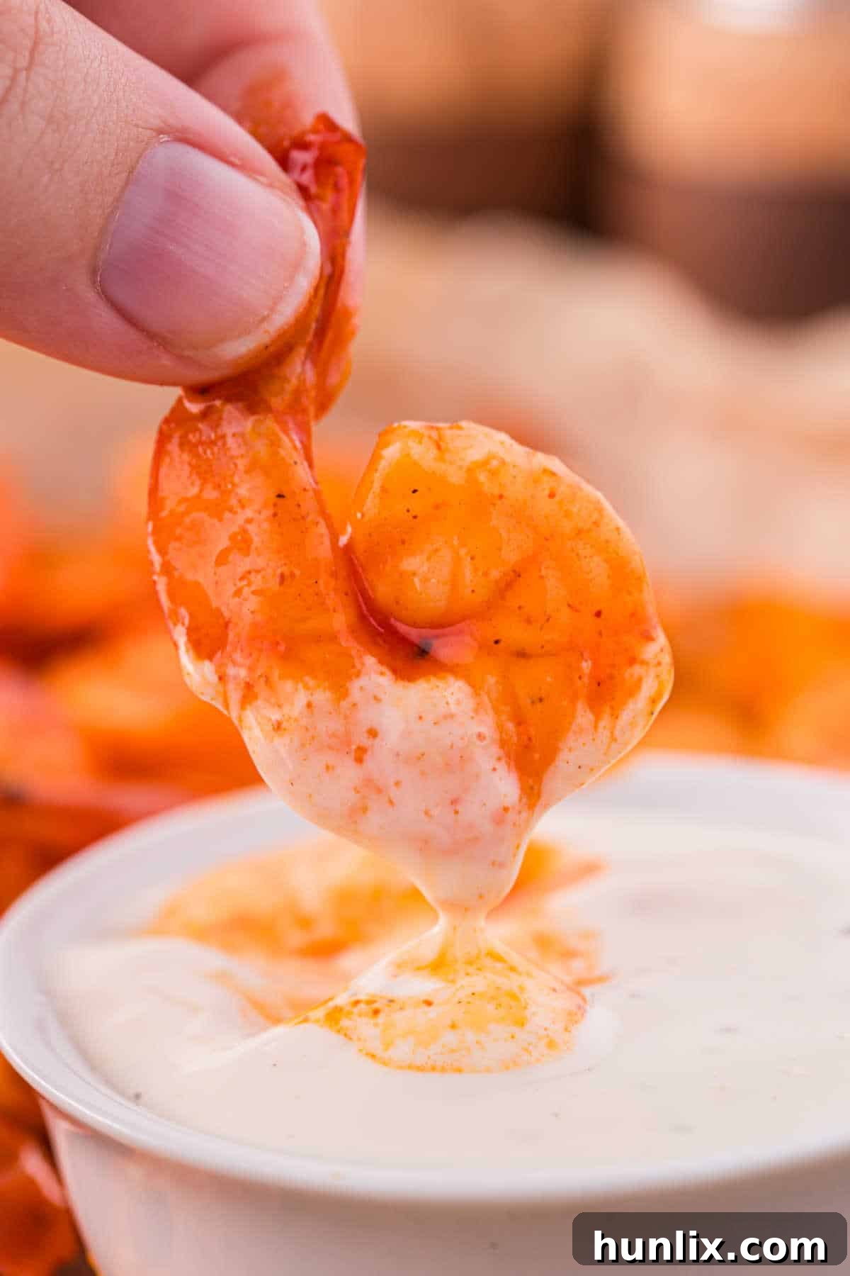 Crimson Glazed Shrimp 8 A hand holding a buffalo shrimp dipping in ranch dipping sauce.